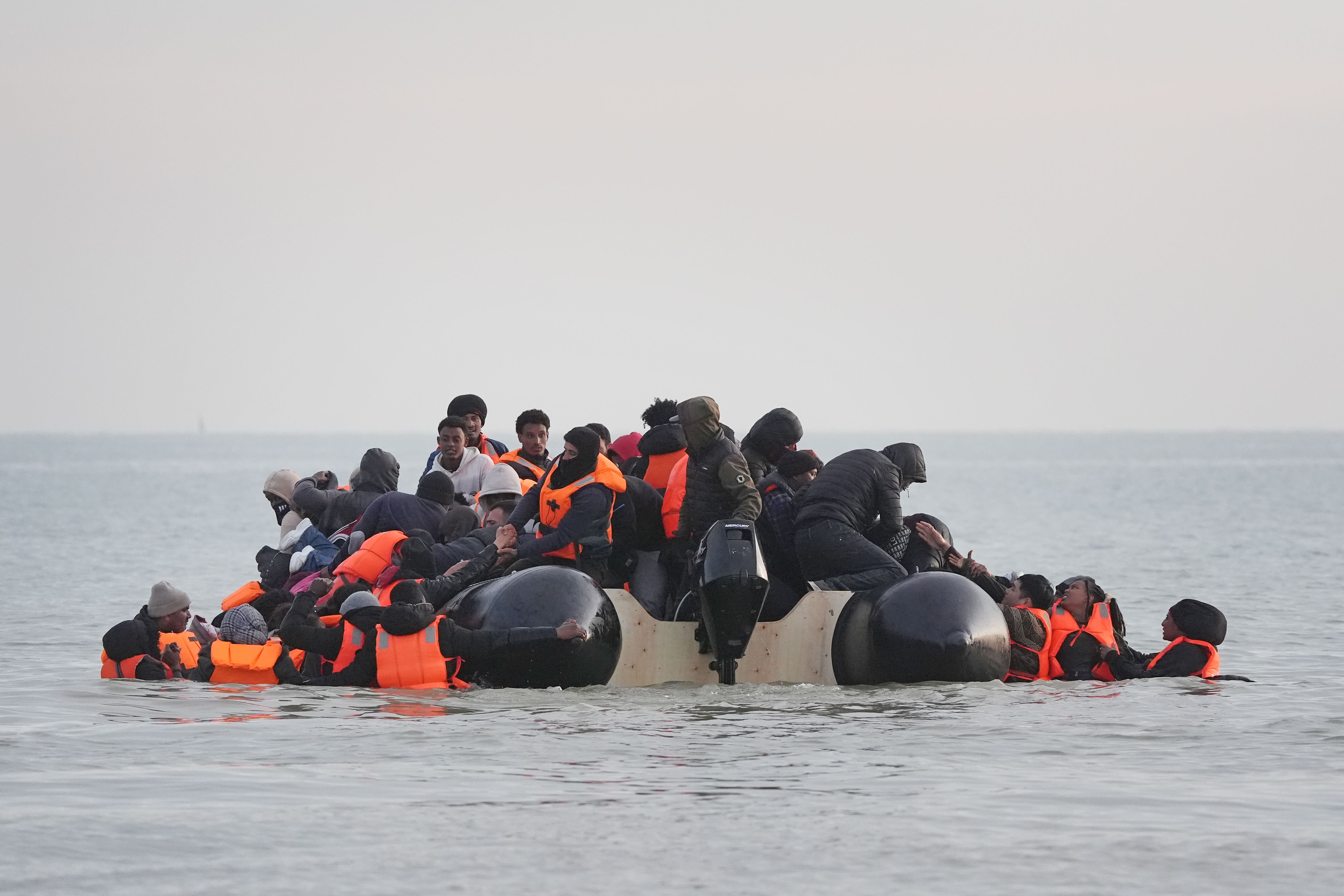 Migrants scramble on board a small boat leaving the beach at Gravelines