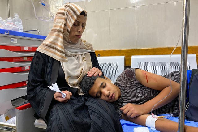 <p>A Palestinian injured by Israeli fire near the aid centre in Rafah is comforted at the Nasser hospital</p>