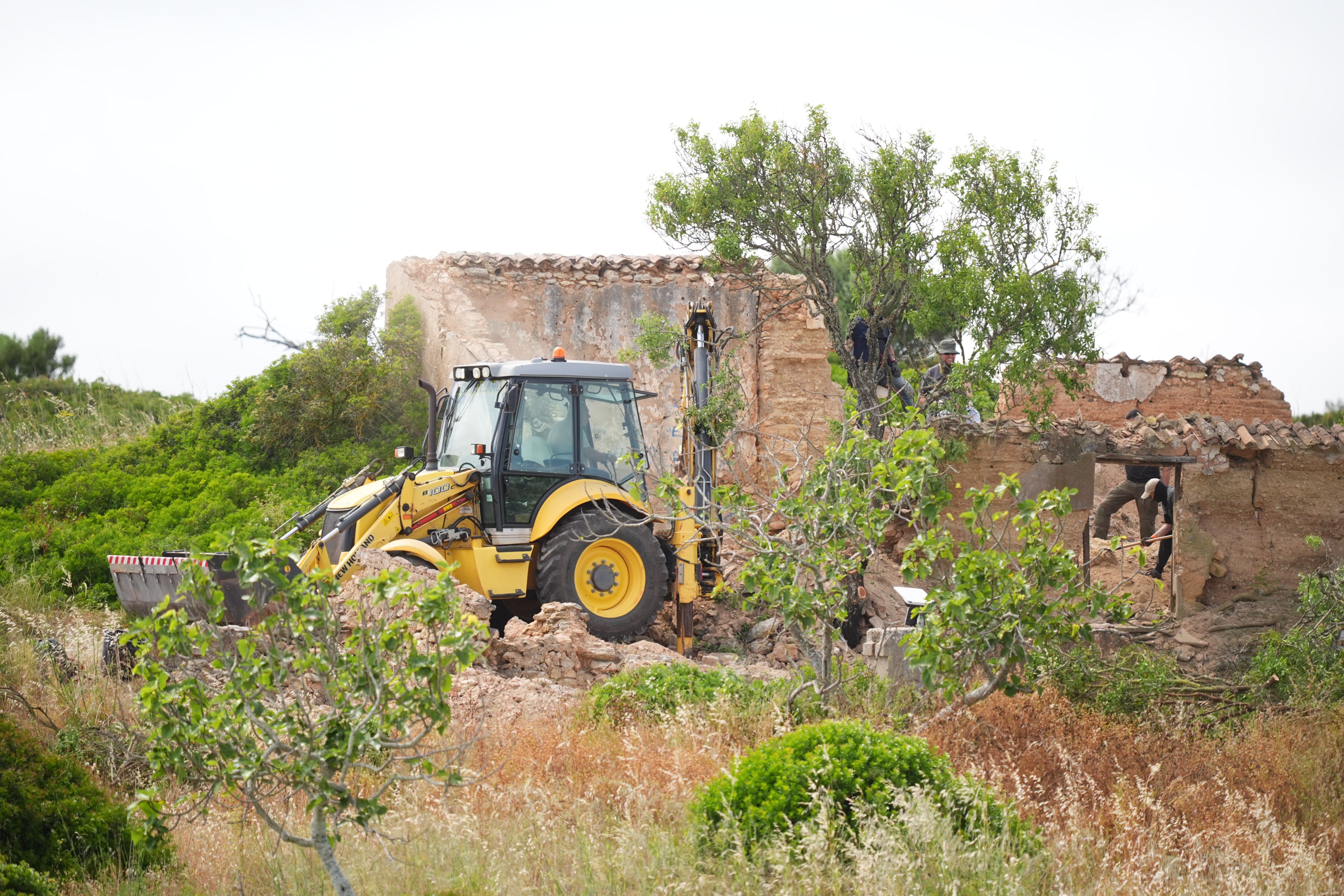 Search teams use a backhoe digger next to a derelict and abandoned property on Wednesday