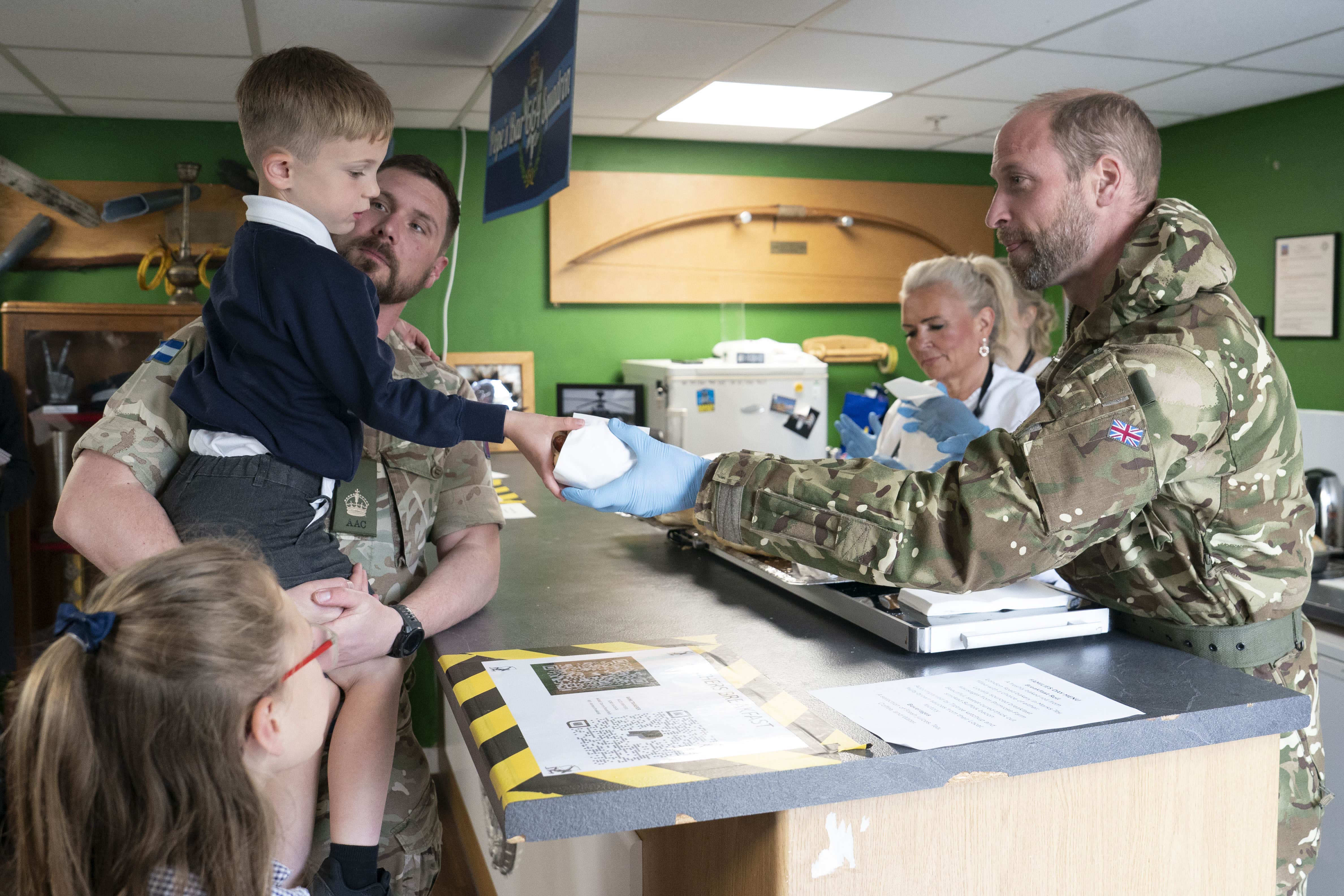 The Prince of Wales hands out rolls with bacon and sausage to military families (Arthur Edwards/The Sun/PA)