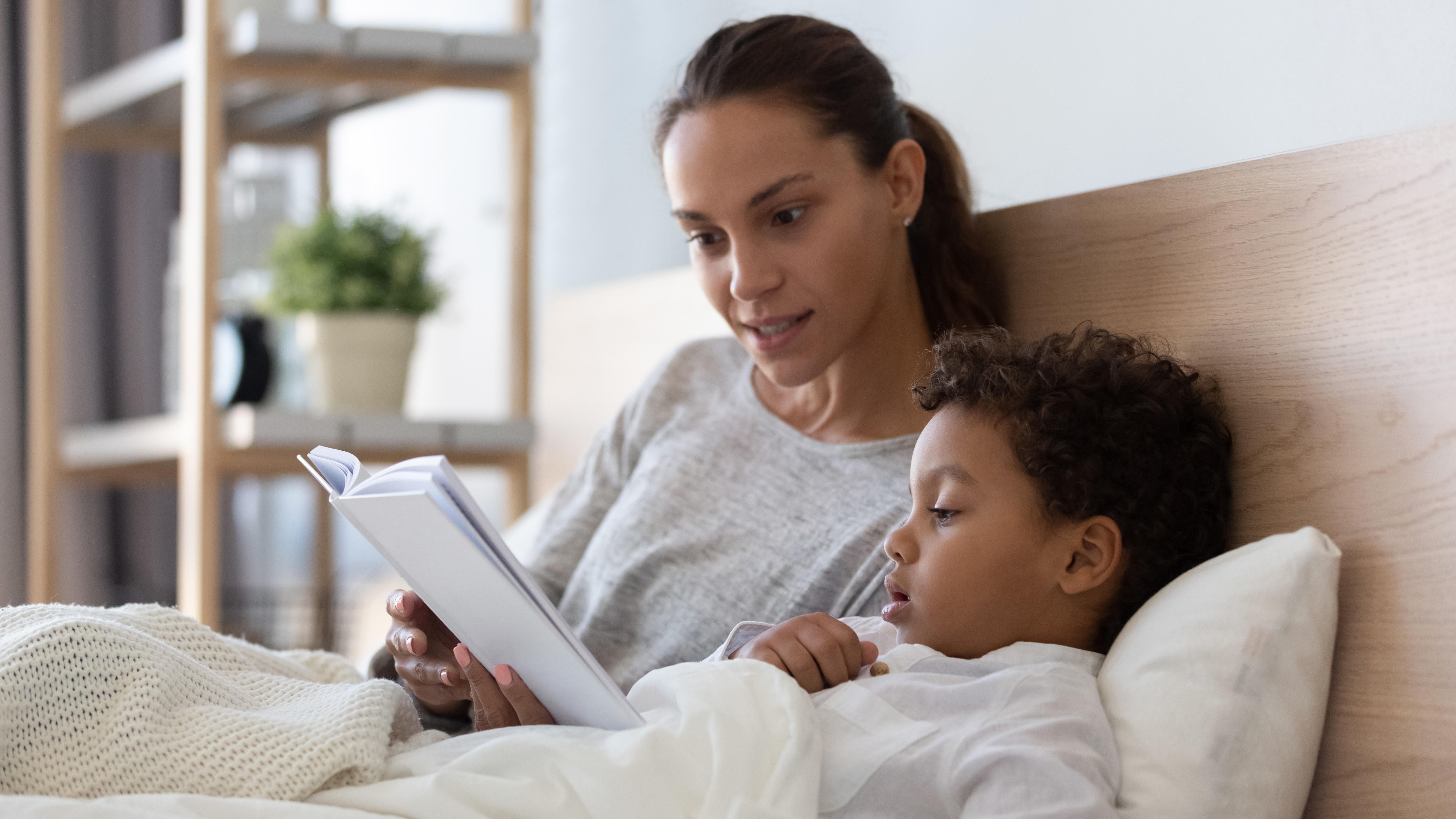 A mum reading a book to her young son in bed