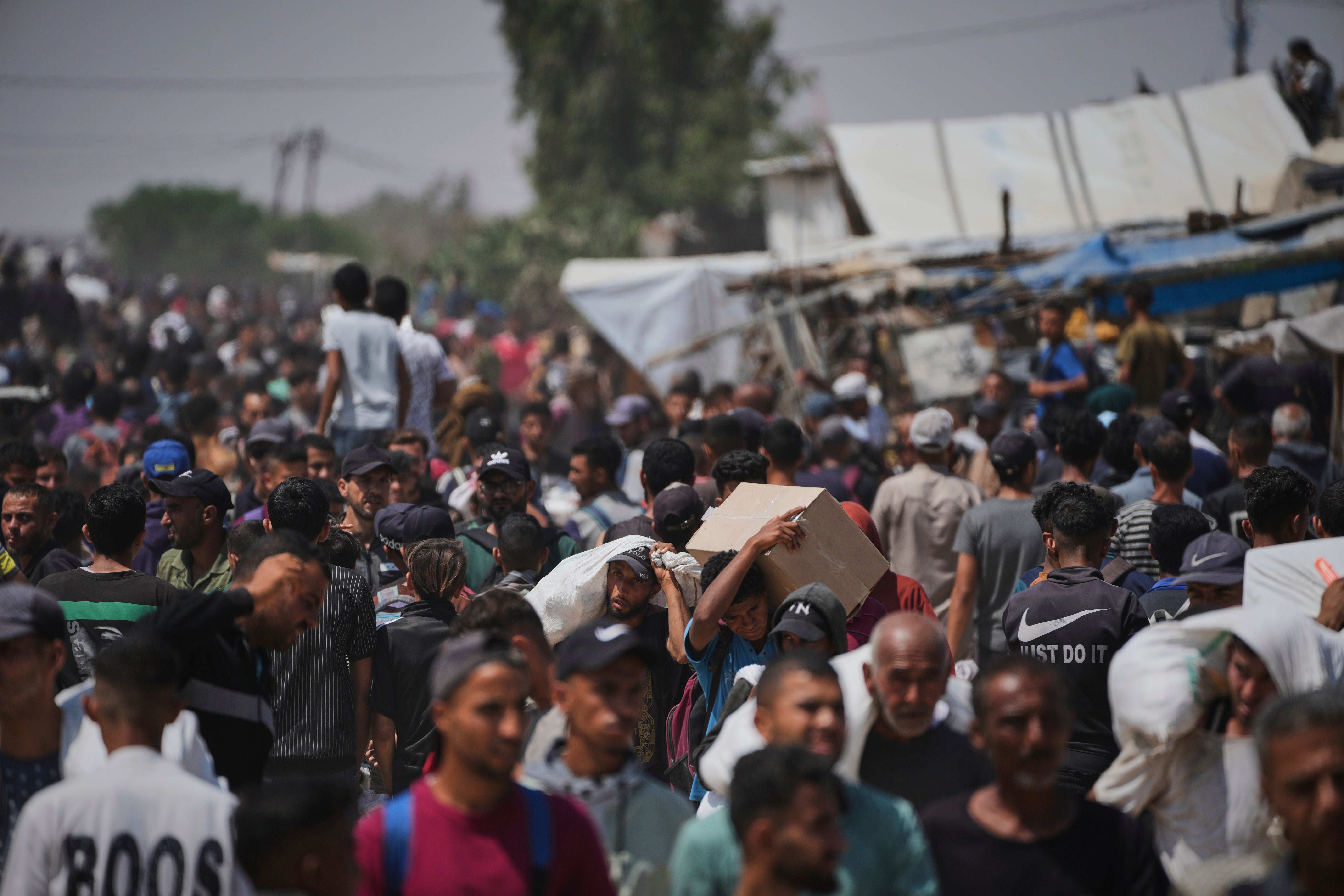 Palestinians carry boxes and bags containing food and humanitarian aid packages delivered by the GHF in Rafah