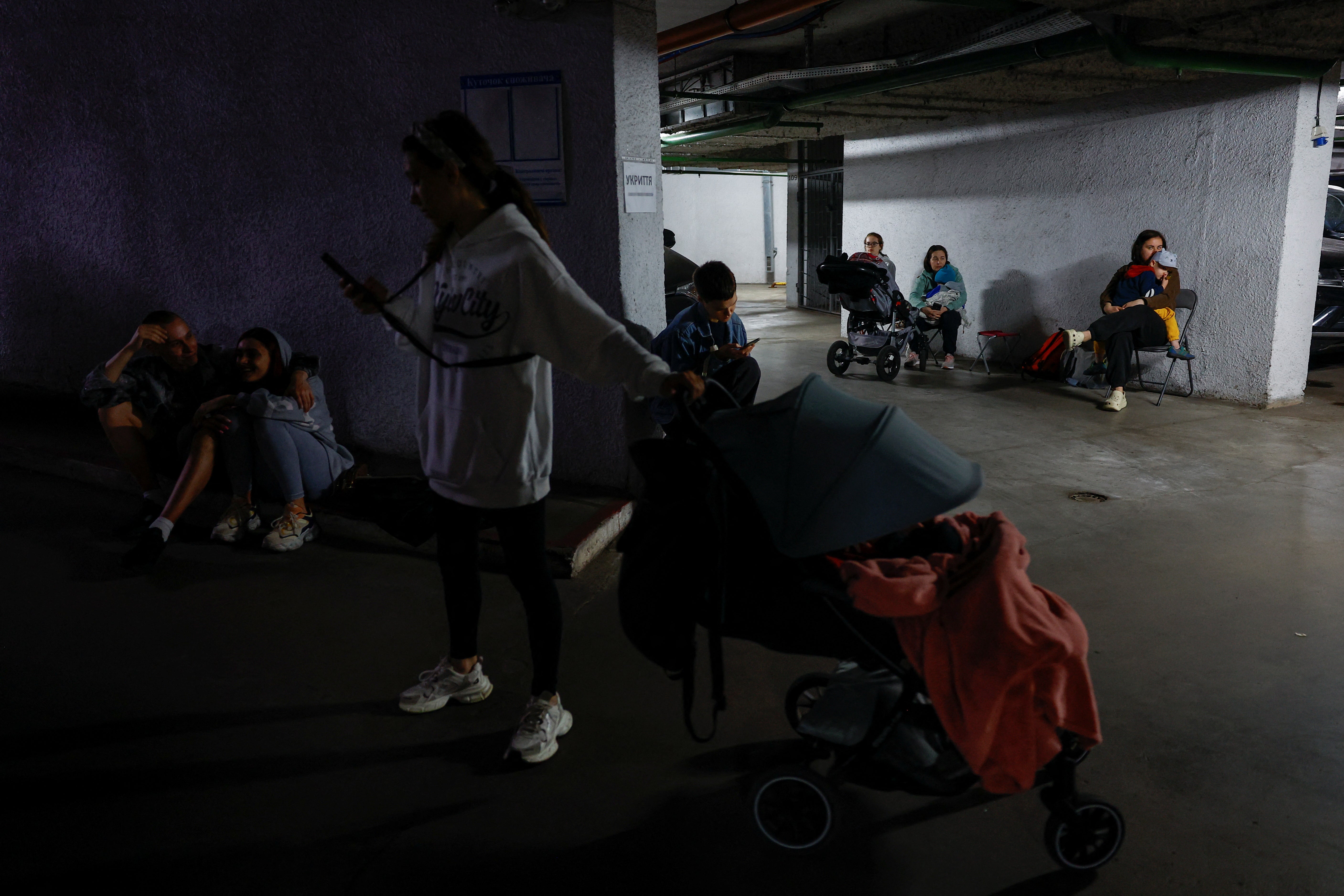 People take shelter in an underground parking lot during a Russian drone and missile attack on Kyiv