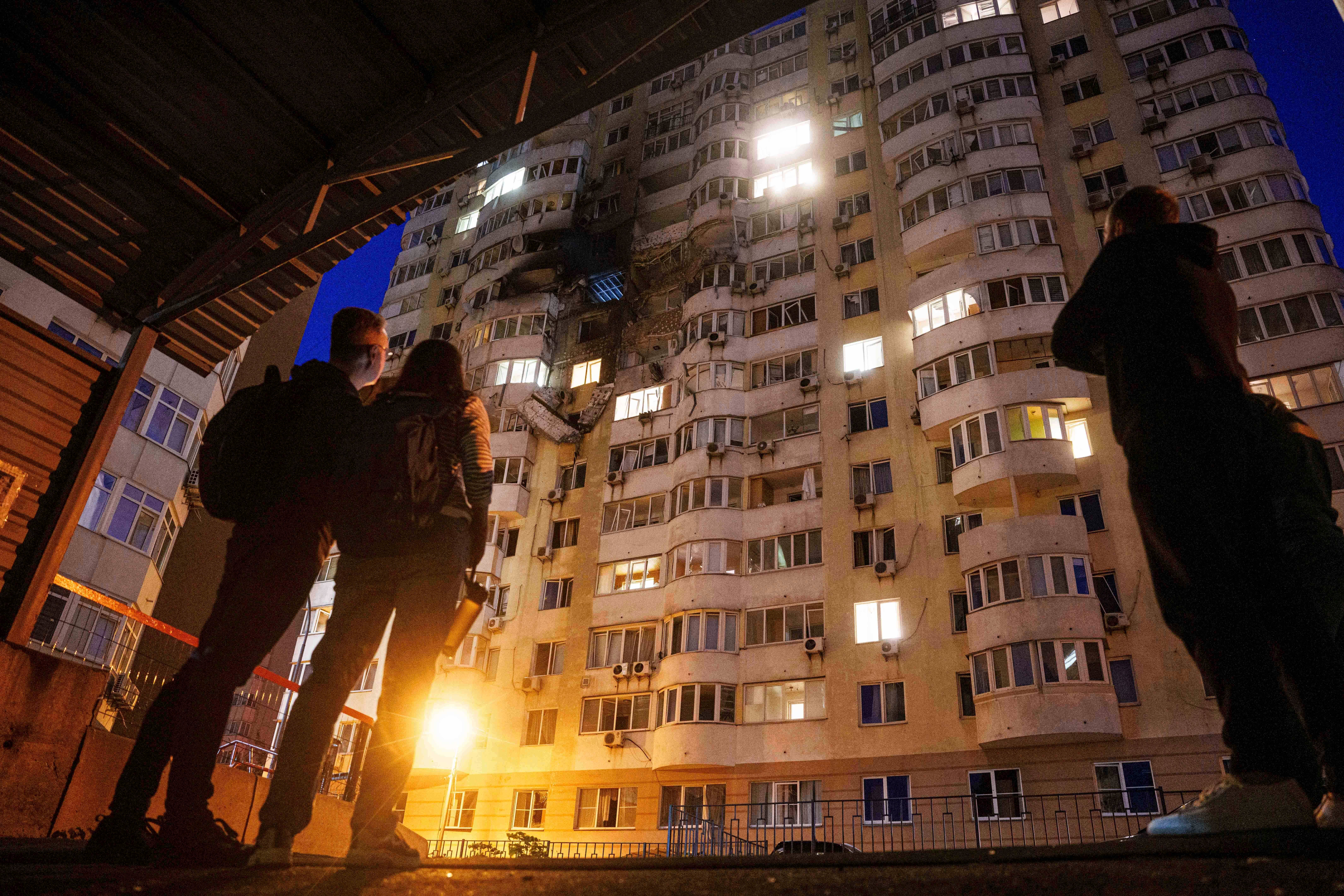 People look at a residential multi-storey building damaged after a Russian drone strike on Kyiv