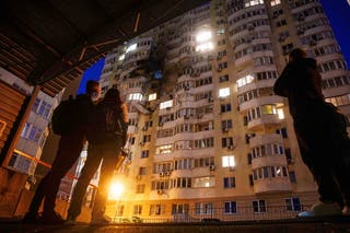 People look at a residential multi-storey building damaged after a Russian drone strike on Kyiv