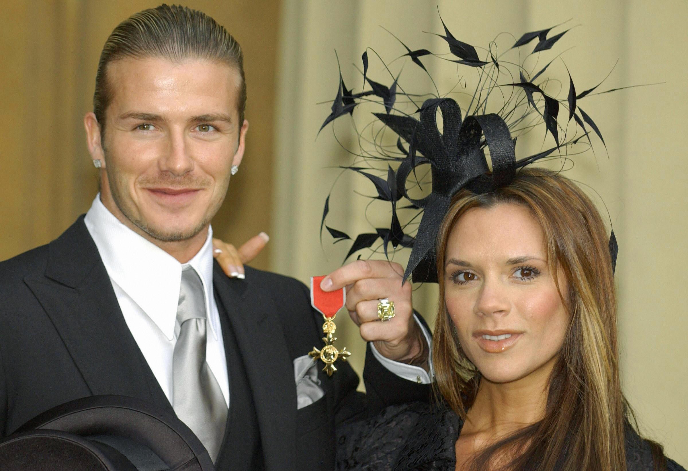 David Beckham stands with his wife, Victoria, as he shows off the OBE he received in November 2003, from Britain's Queen Elizabeth II at London's Buckingham Palace