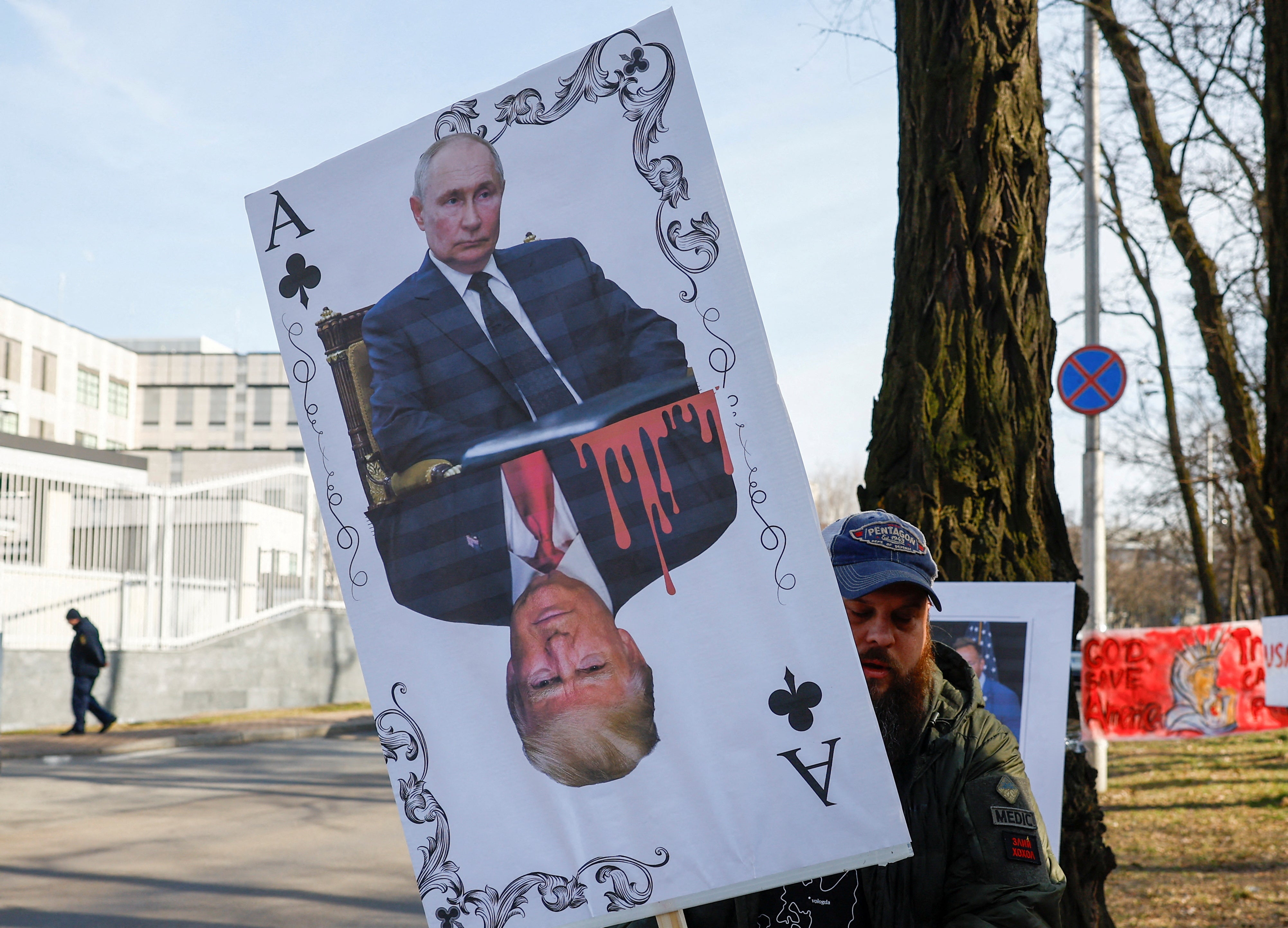 Demonstrator holds banner depicting a playing card with portraits of Russian president Vladimir Putin and U.S president Donald Trump during a rally