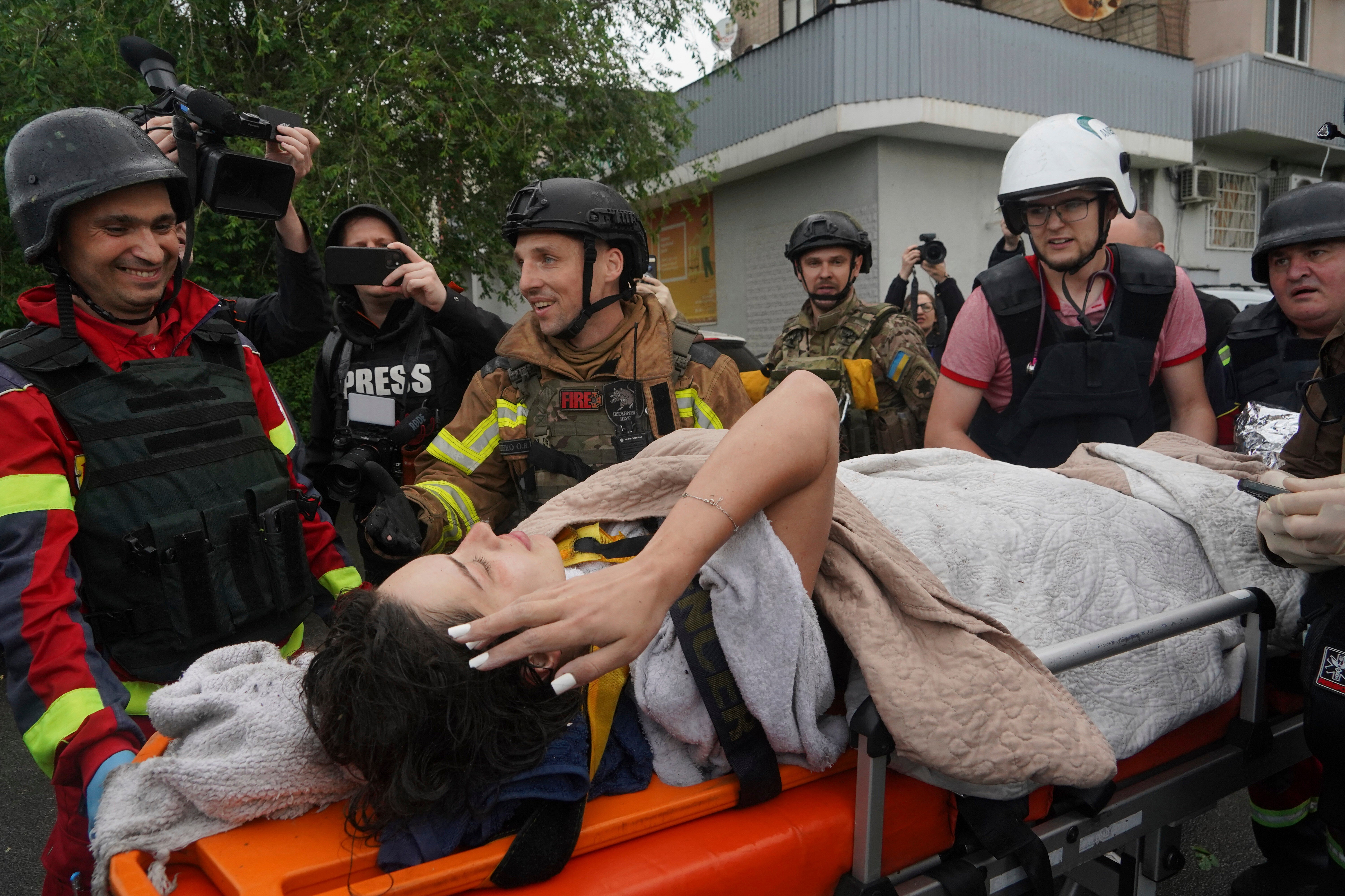 Rescuers carry a wounded woman after Russian attack that hit a residential building in Kharkiv