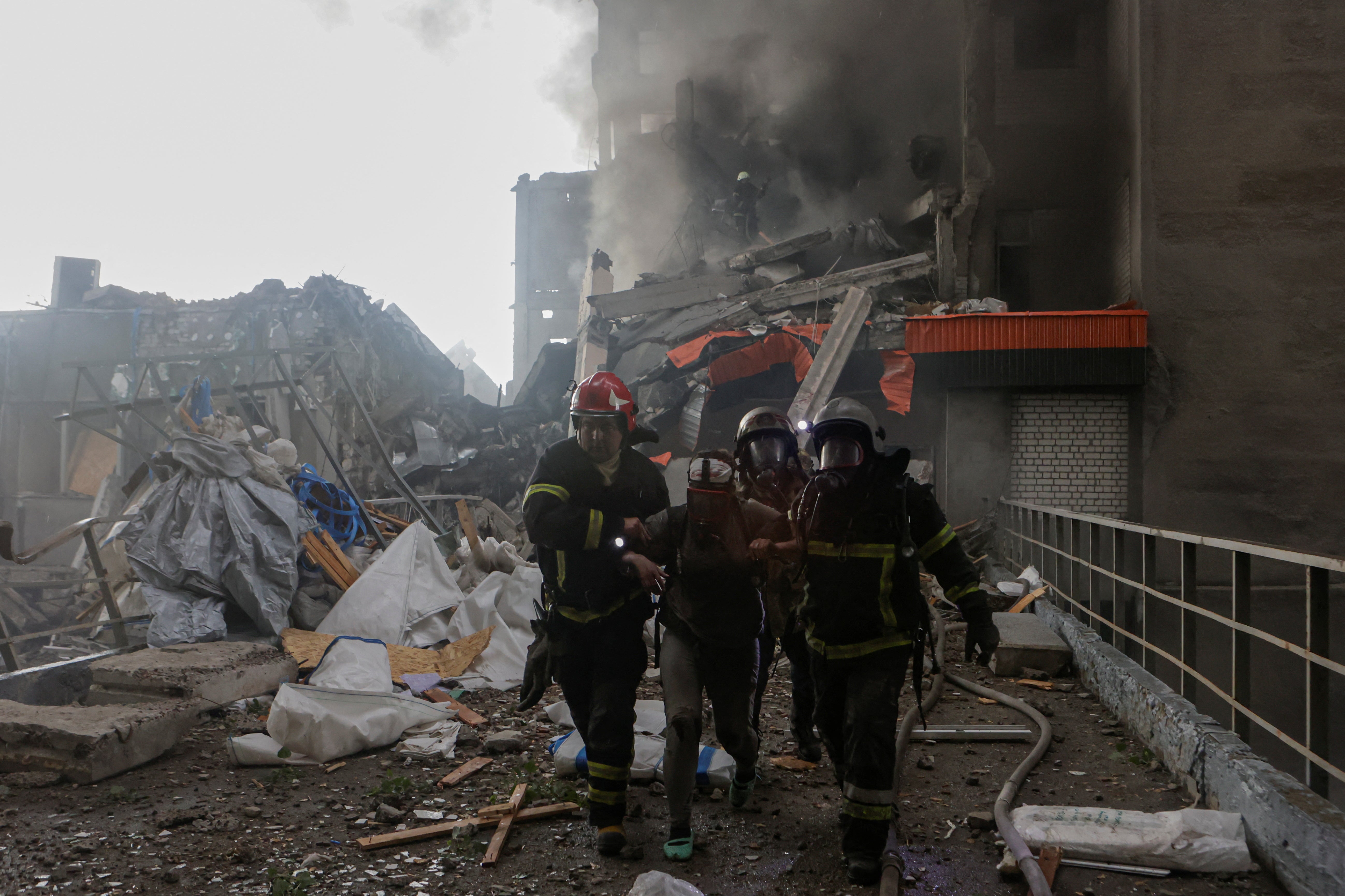 Rescuers assist an injured resident after she was released from debris of a building hit by a Russian drone strike
