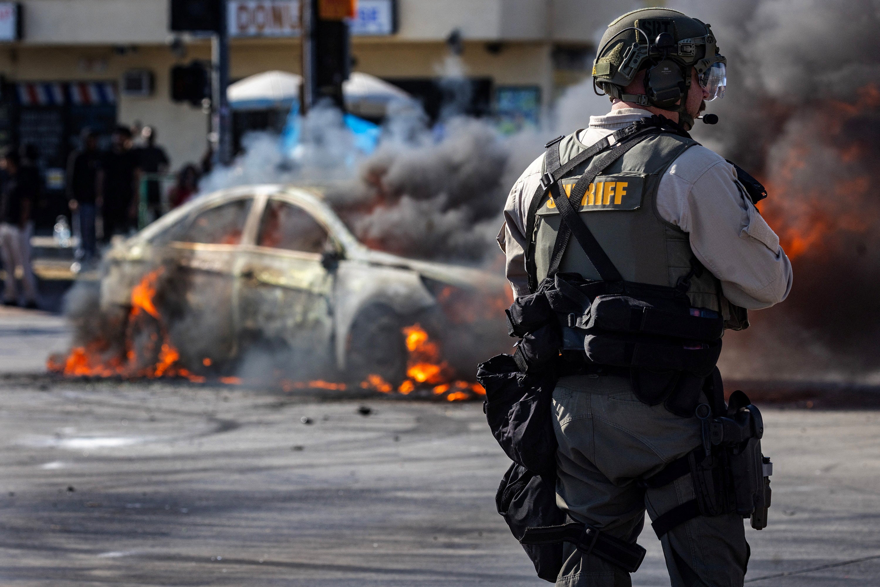 The smoke comes out of the burning car on Atlantic Boulevard, Los Angeles, on Saturday during a meeting by the demonstrators and education and law enforcement after attacking on the Ice Agents