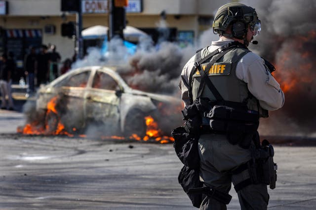 <p>Smoke rises from a burning car on Atlantic Boulevard during a standoff by protesters and law enforcement, LA, California, US, June 7, 2025</p>
