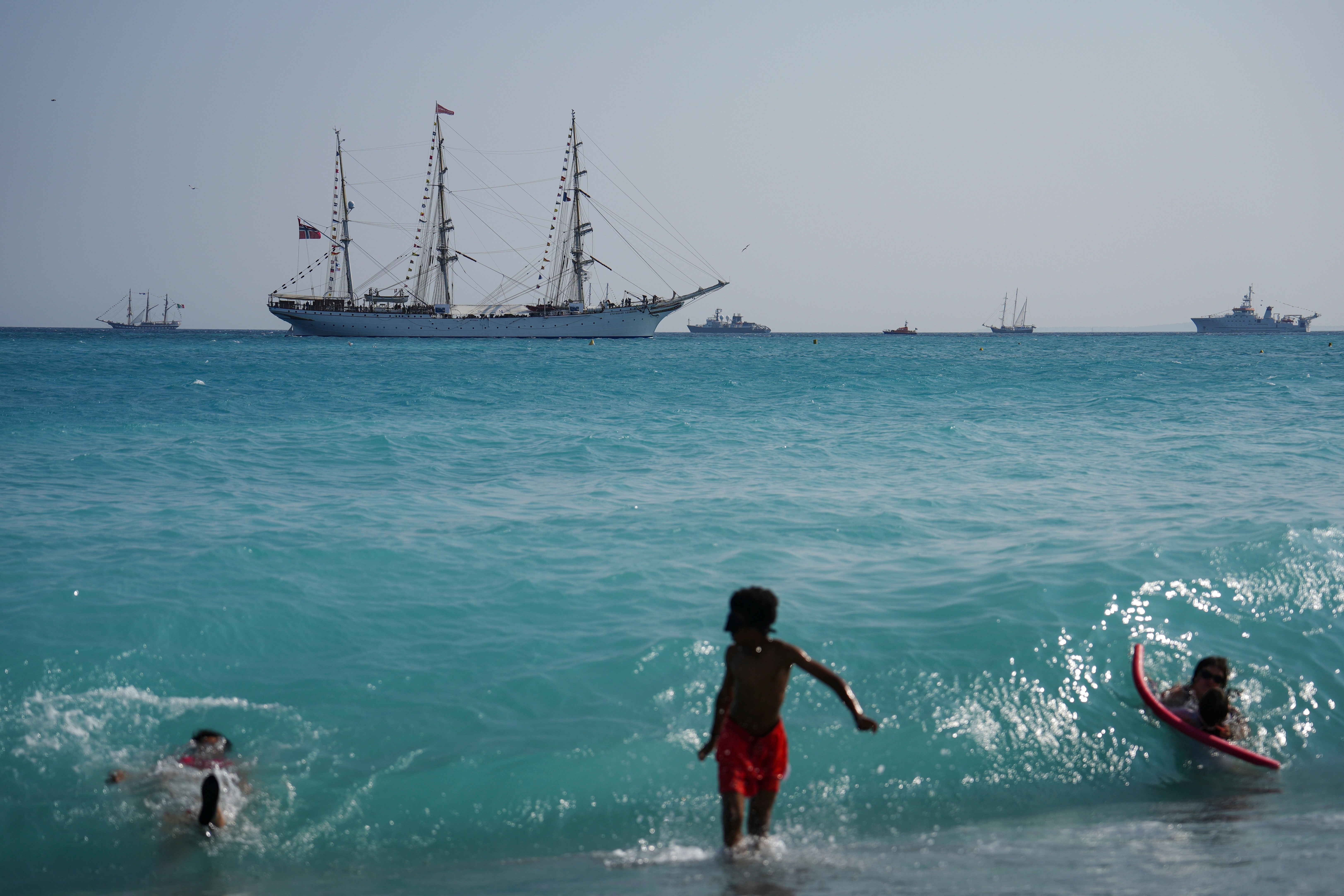 People swim as vessels sail during the