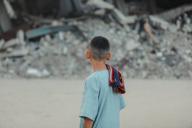<p>A Palestinian boy walks to perform the Eid al-Adha prayers amid the rubble of destroyed buildings in Gaza</p>