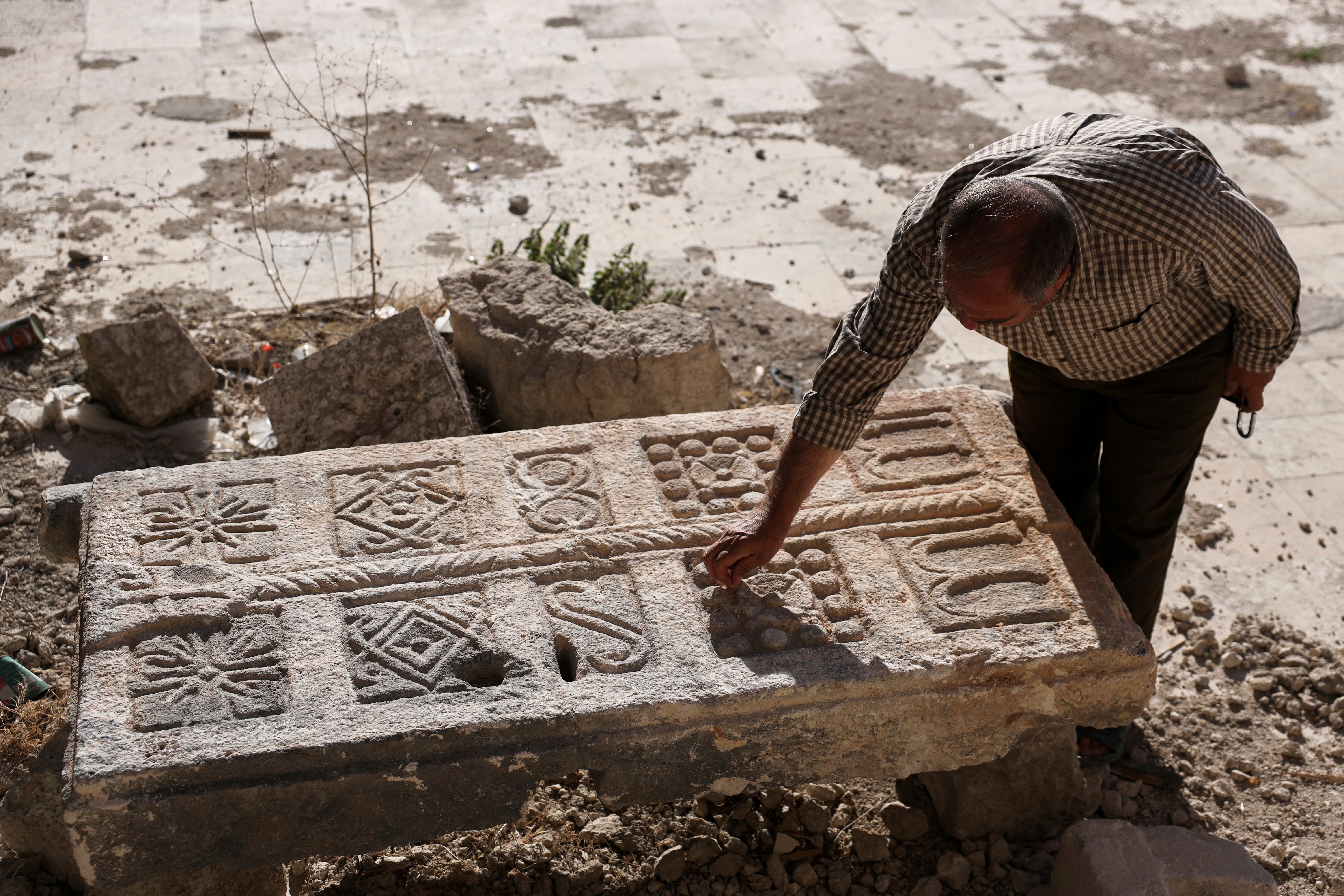 A guard inspects an engraved stone in the tomb complex