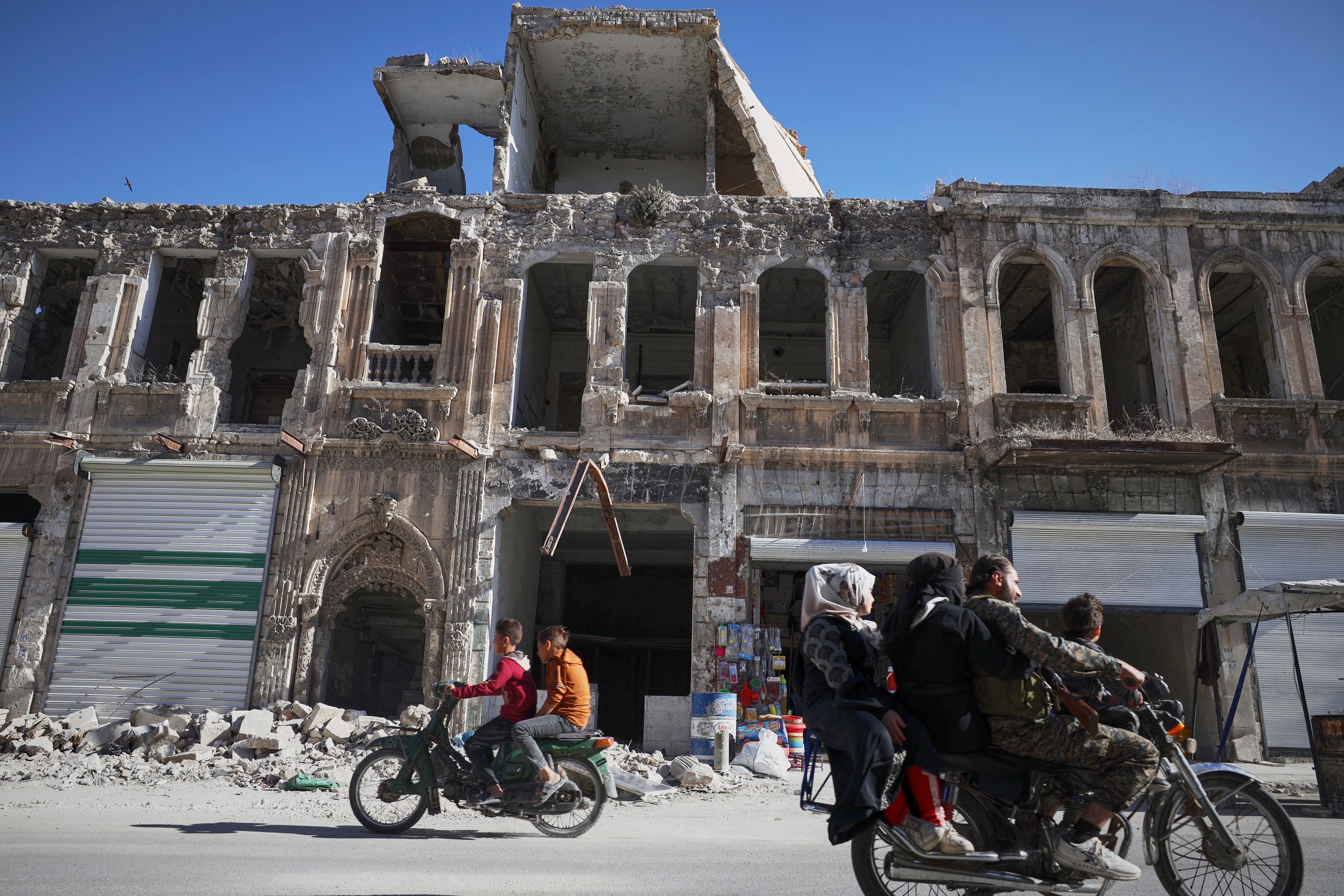 Residents drive past the war-damaged ancient market of Maarat al-Numan, near the site where a Byzantine underground tomb complex was discovered