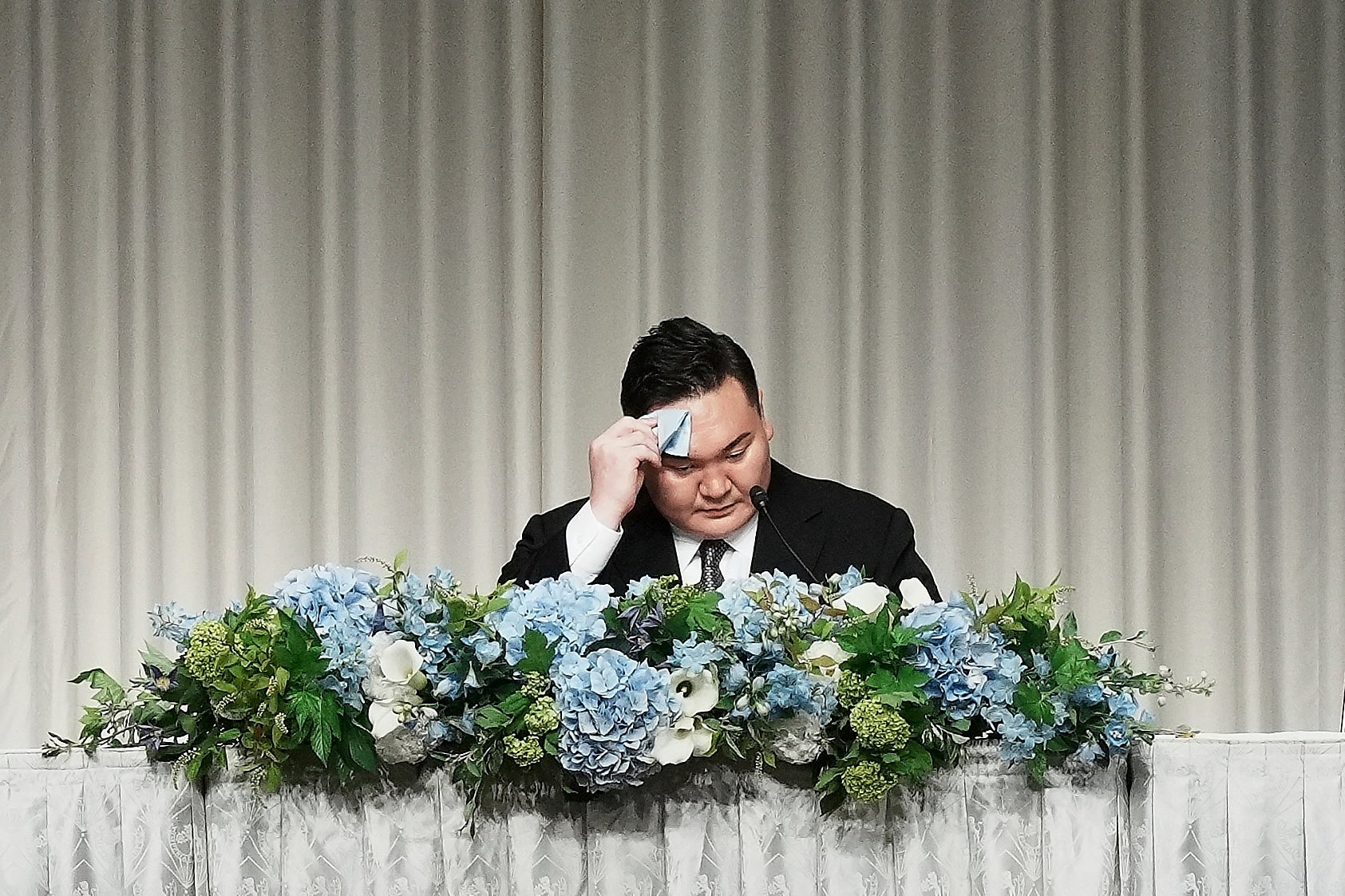 Hakuho Sho, um aposentado 'Yokozuna' ou Grande Campeão do Sumo Hakuho, enxuga seu rosto durante uma conferência de imprensa em Tóquio, segunda -feira, 9 de junho de 2025, para transmitir uma mensagem de despedida após a aceitação relatada de sua demissão e descrever seus planos futuros. (AP Photo/Eugene Hoshiko)