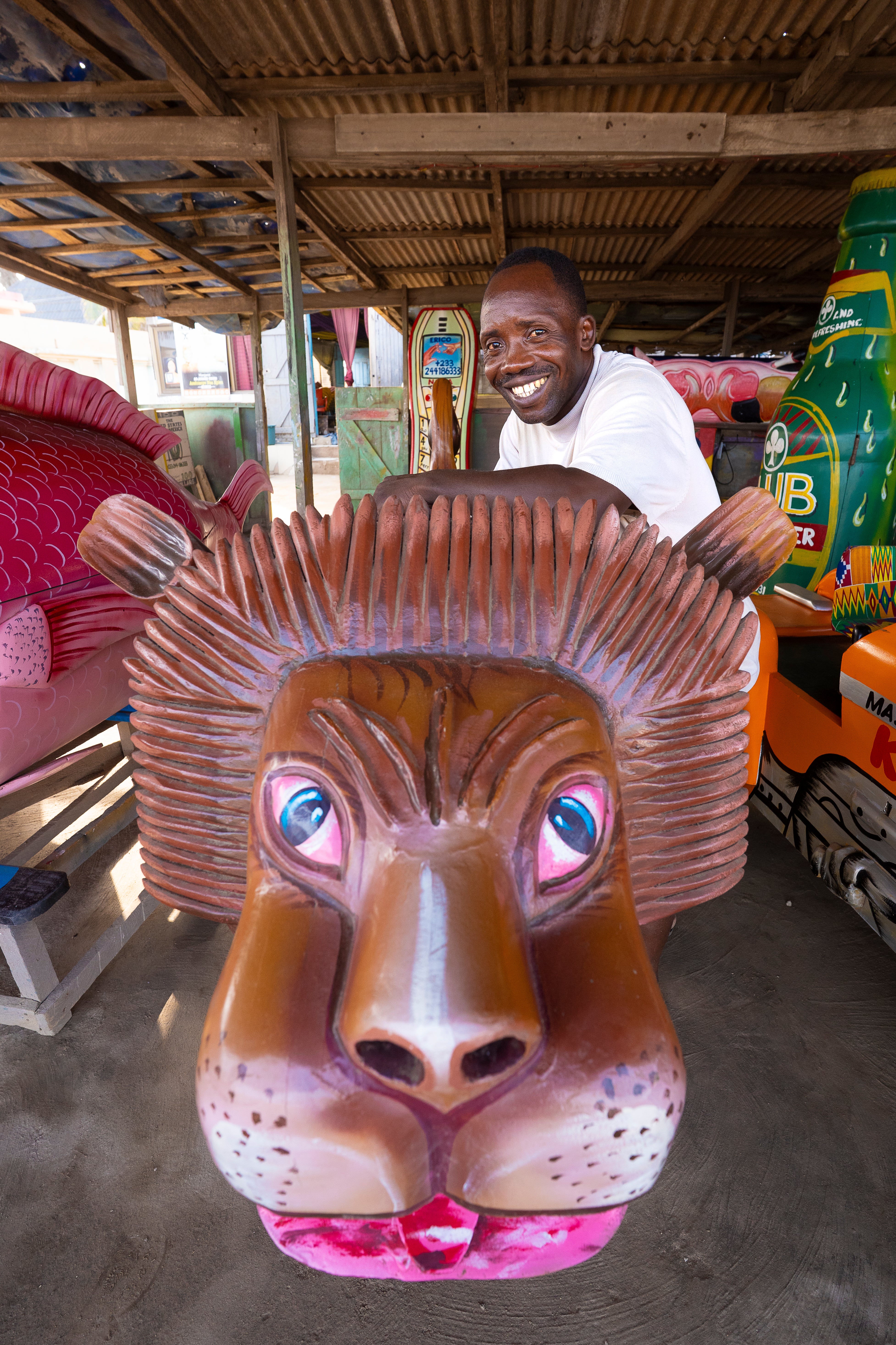 Eric Kpakpo Adotey smiles alongside one of his coffin creations