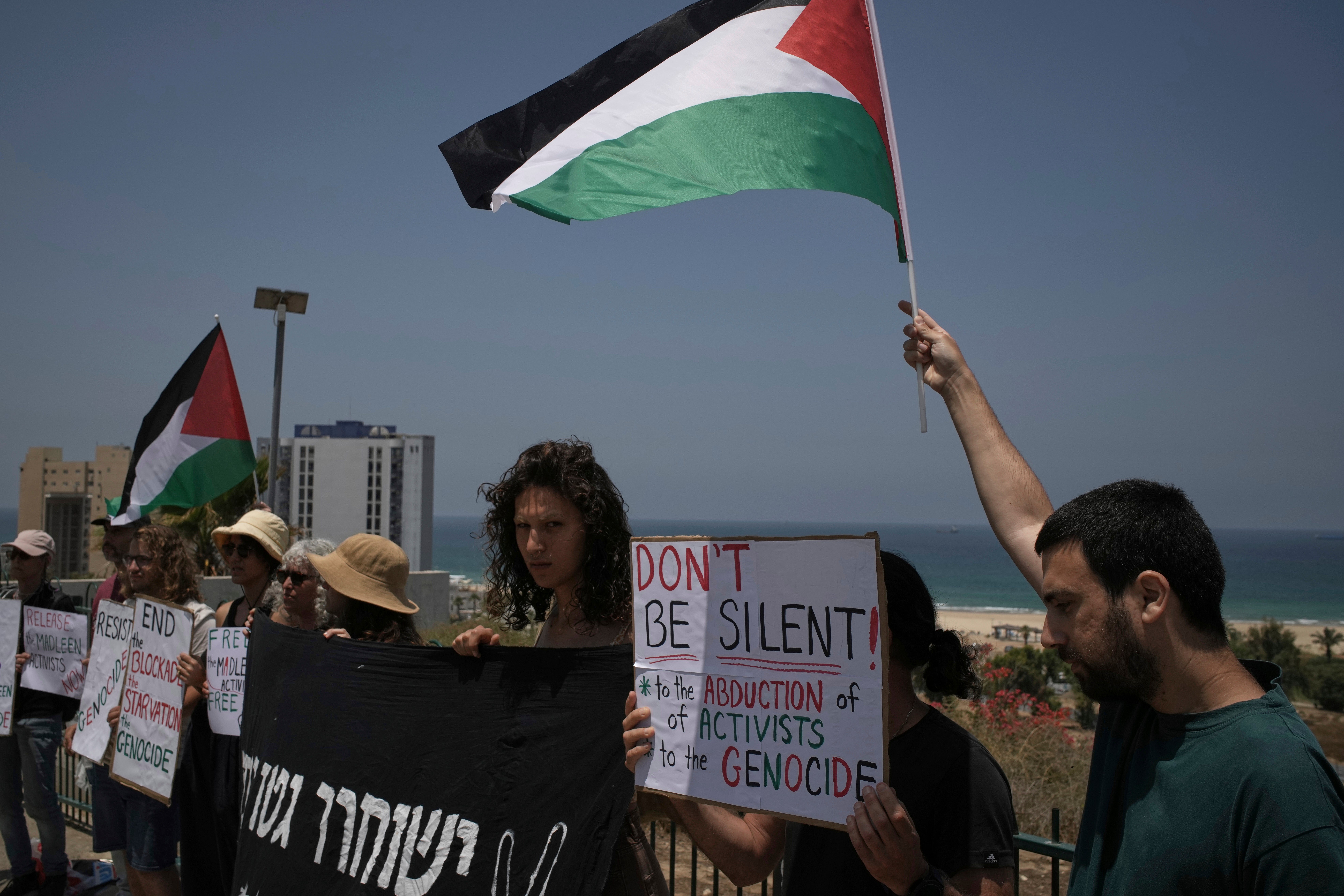 People wave the Palestinian flag and hold signs in support of Greta Thunberg and other activists who tried to deliver aid to Gaza before their ship was seized and they were detained by Israeli forces, near the port of Ashdod