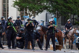 Police fire non-lethal weapons at activists hiding behind a makeshift barricade during protests sparked by immigration raids in Los Angeles, California, USA, 08 June 2025