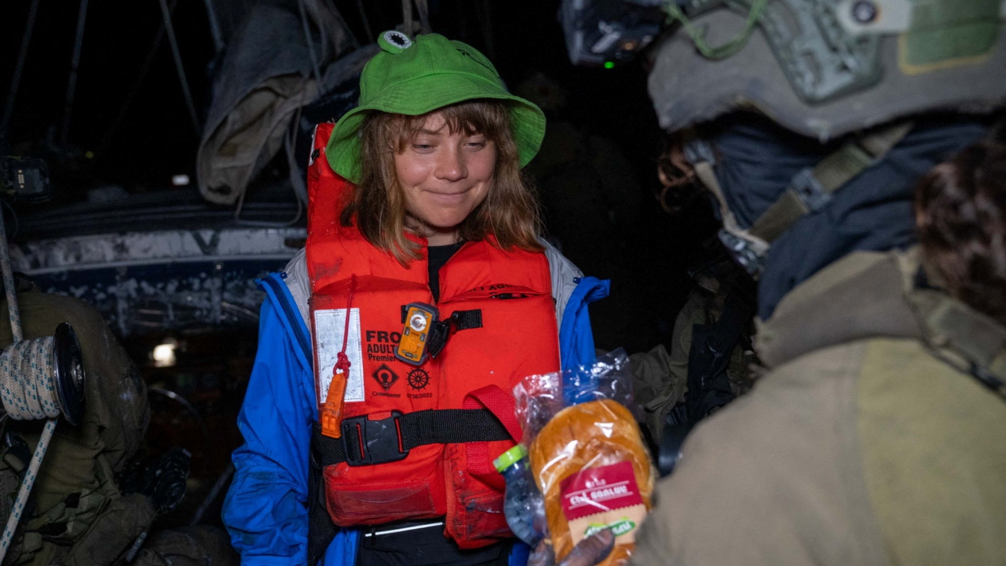An Israeli solider passes a bun to Greta Thunberg onboard the Gaza-bound British-flagged yacht