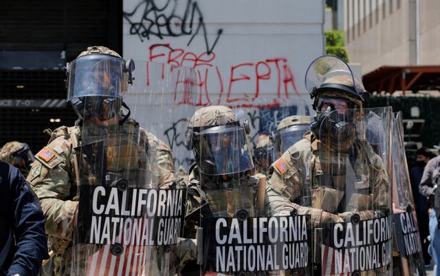 <p>Members of the California National Guard stand together, as a demonstration against federal immigration sweeps takes place, outside the Edward R. Roybal federal building, after their deployment by US President Donald Trump.</p>