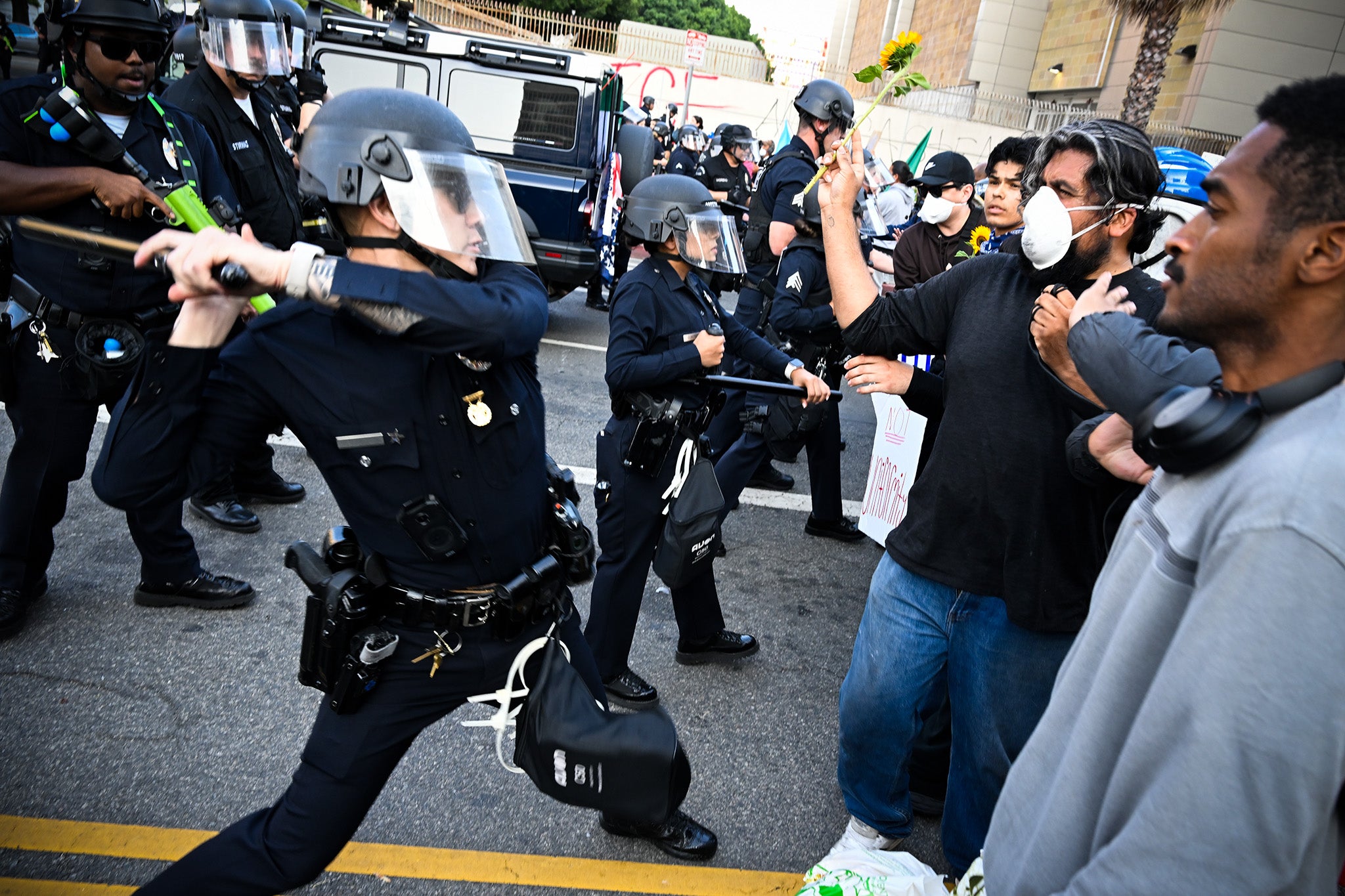 Anti-ICE protester holds up a sunflower during a clash with police near the Federal Building and detention center in Los Angeles