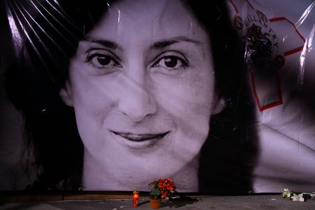 <p>Flowers and a candle lie in front of a portrait of slain investigative journalist Daphne Caruana Galizia during a vigil outside the law courts in Valletta, Malta</p>