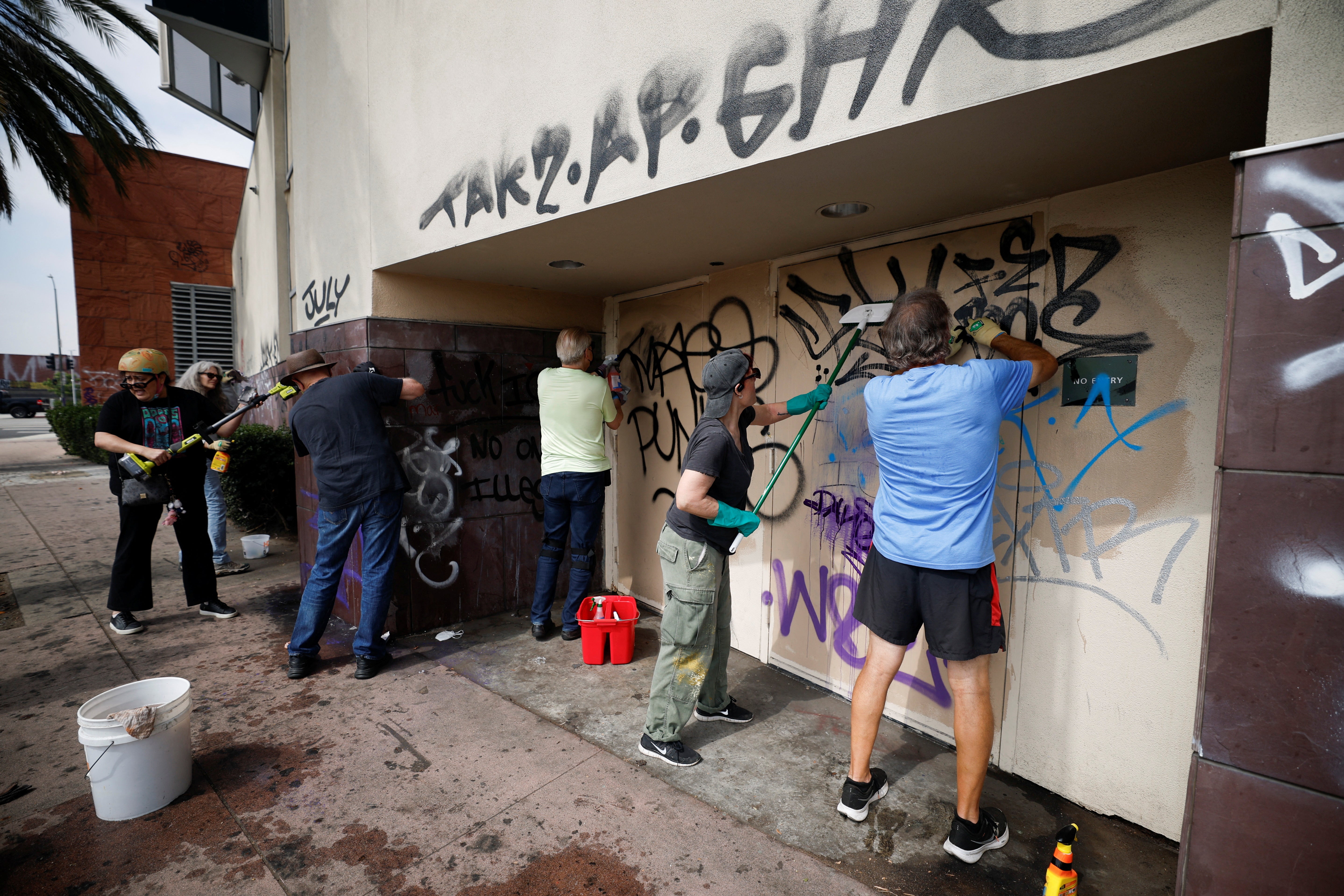 Artists and social activists clean graffiti after days of protests against federal immigration sweeps and the deployment of the California National Guard and U.S. Marines, outside the Japanese American National Museum in Little Tokyo, Los Angeles