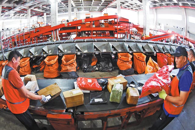 <p>Staff members sort packages at a delivery distribution centre in Lianyungang, Jiangsu province</p>