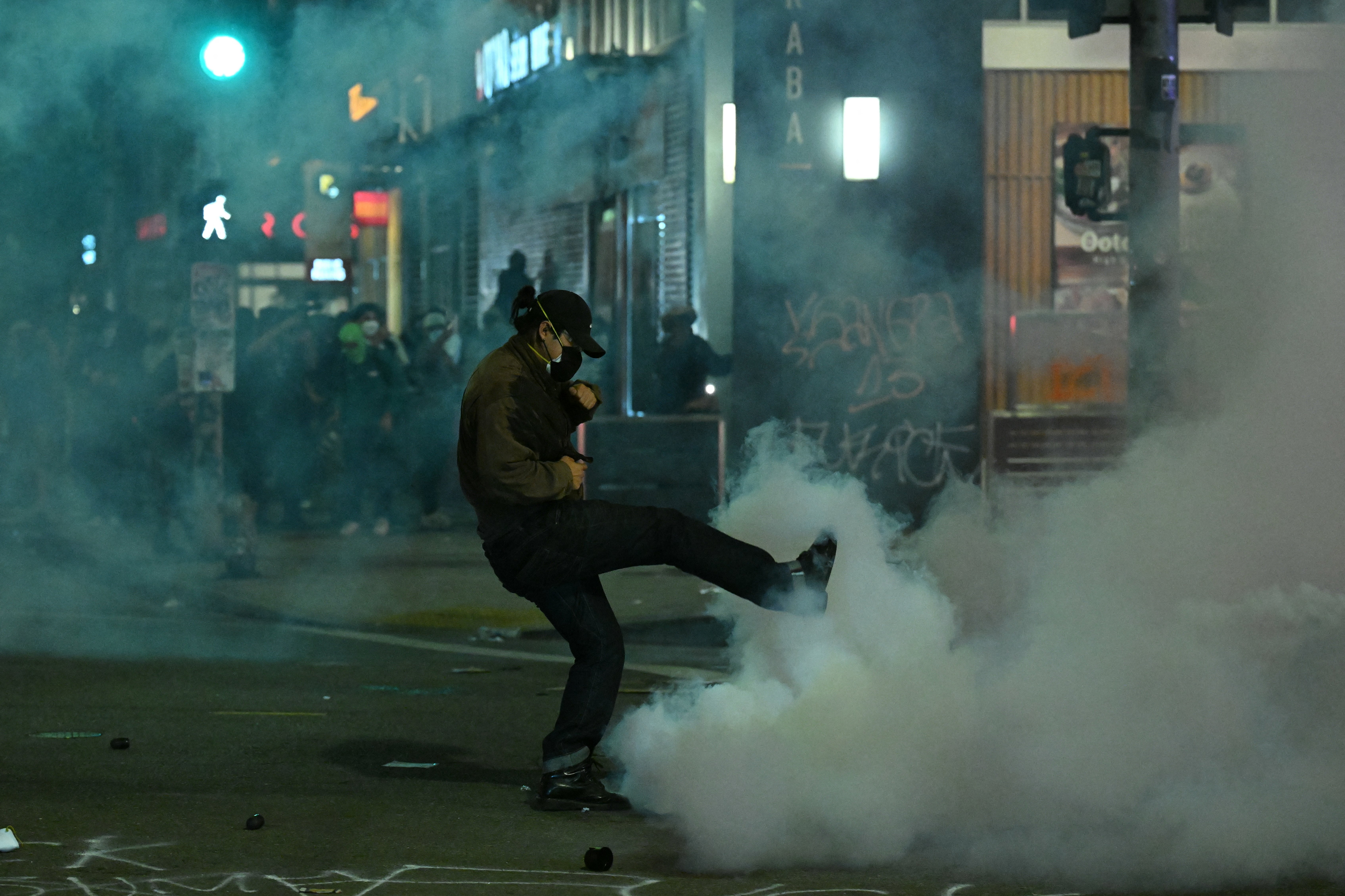 A protester kicks a canister during a protest in response to federal immigration operations in the Little Tokyo neighborhood of downtown Los Angeles