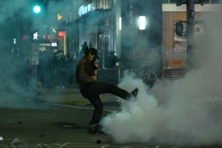 A protester kicks a canister during a protest in response to federal immigration operations in the Little Tokyo neighborhood of downtown Los Angeles