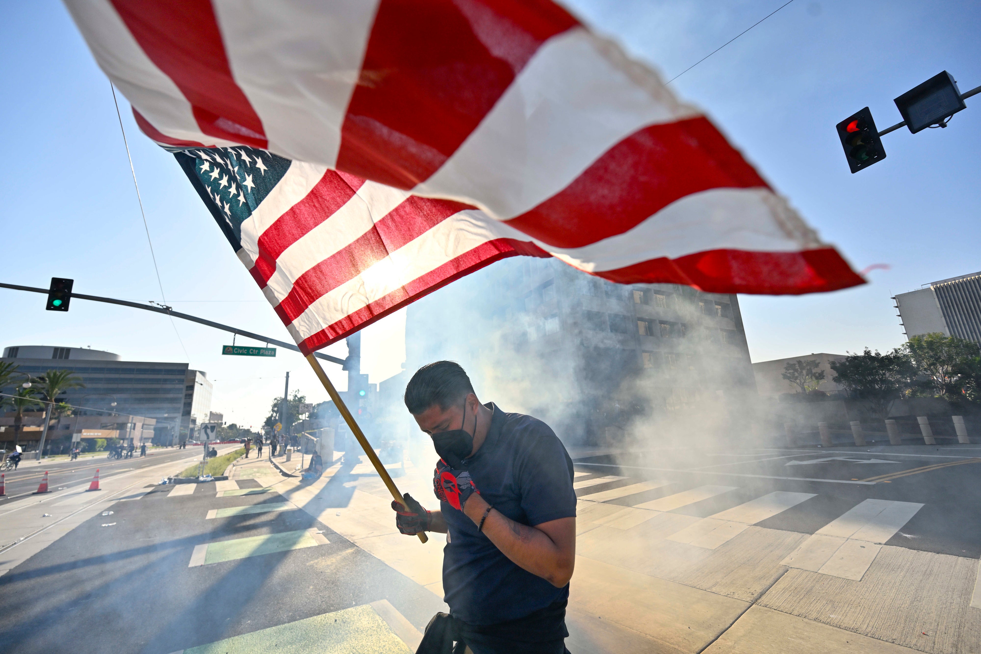 A protester raises the U.S. flag after police use tear gas and flash-bangs at the Federal Building in Santa Ana, California