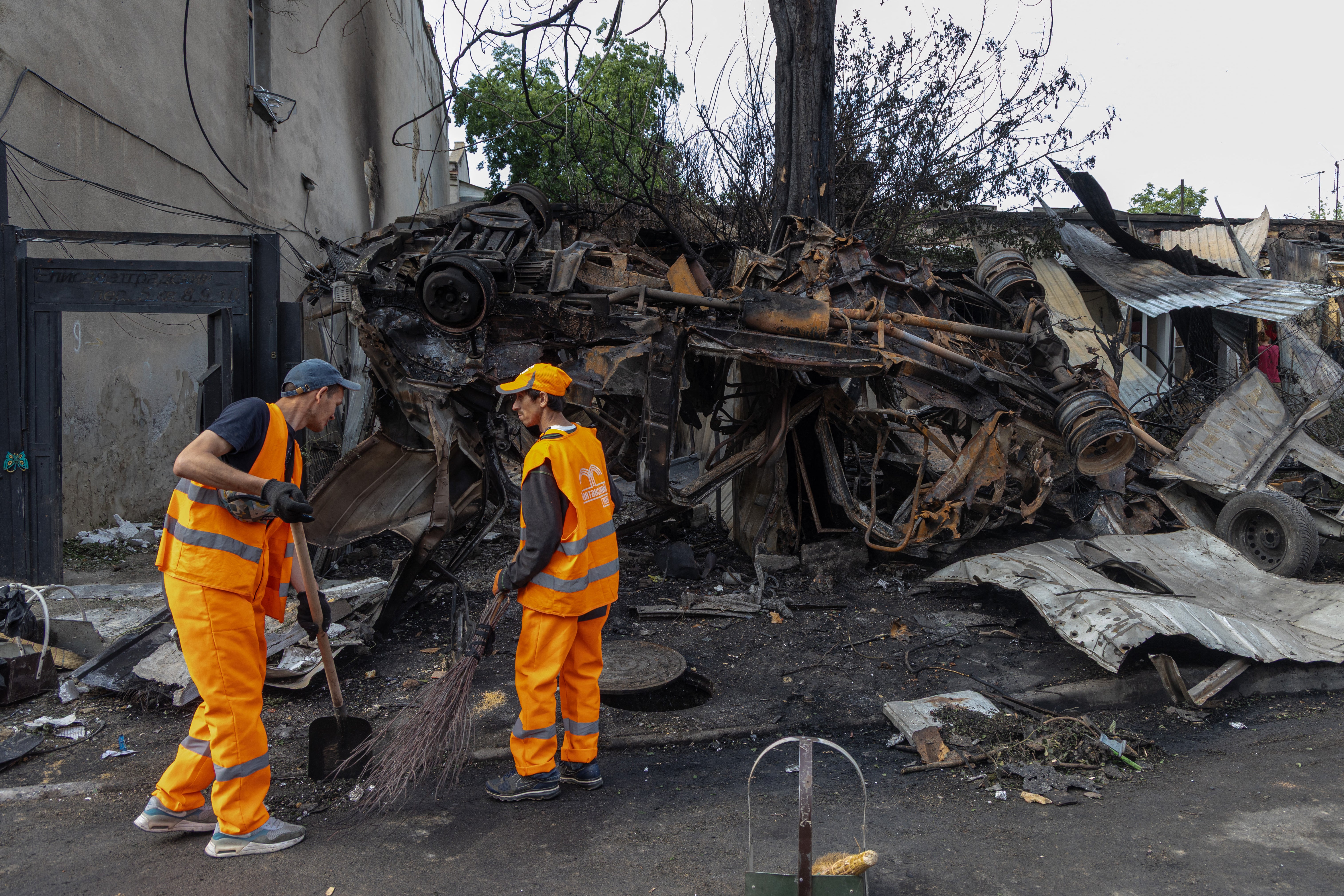 Ukrainian rescuers clean the roads at the site of a drone strike