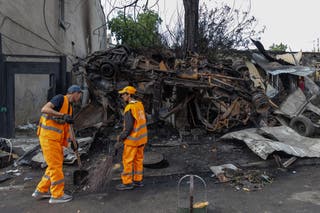 Ukrainian rescuers clean the roads at the site of a drone strike