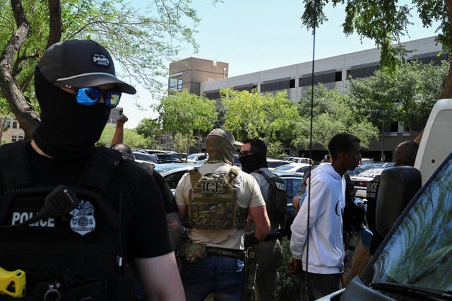 <p>Masked law enforcement officers, including HSI and ICE agents, take people into custody at an immigration court in Phoenix, Arizona. Agents are reportedly using an app to track down immigrants and then arrest them</p>