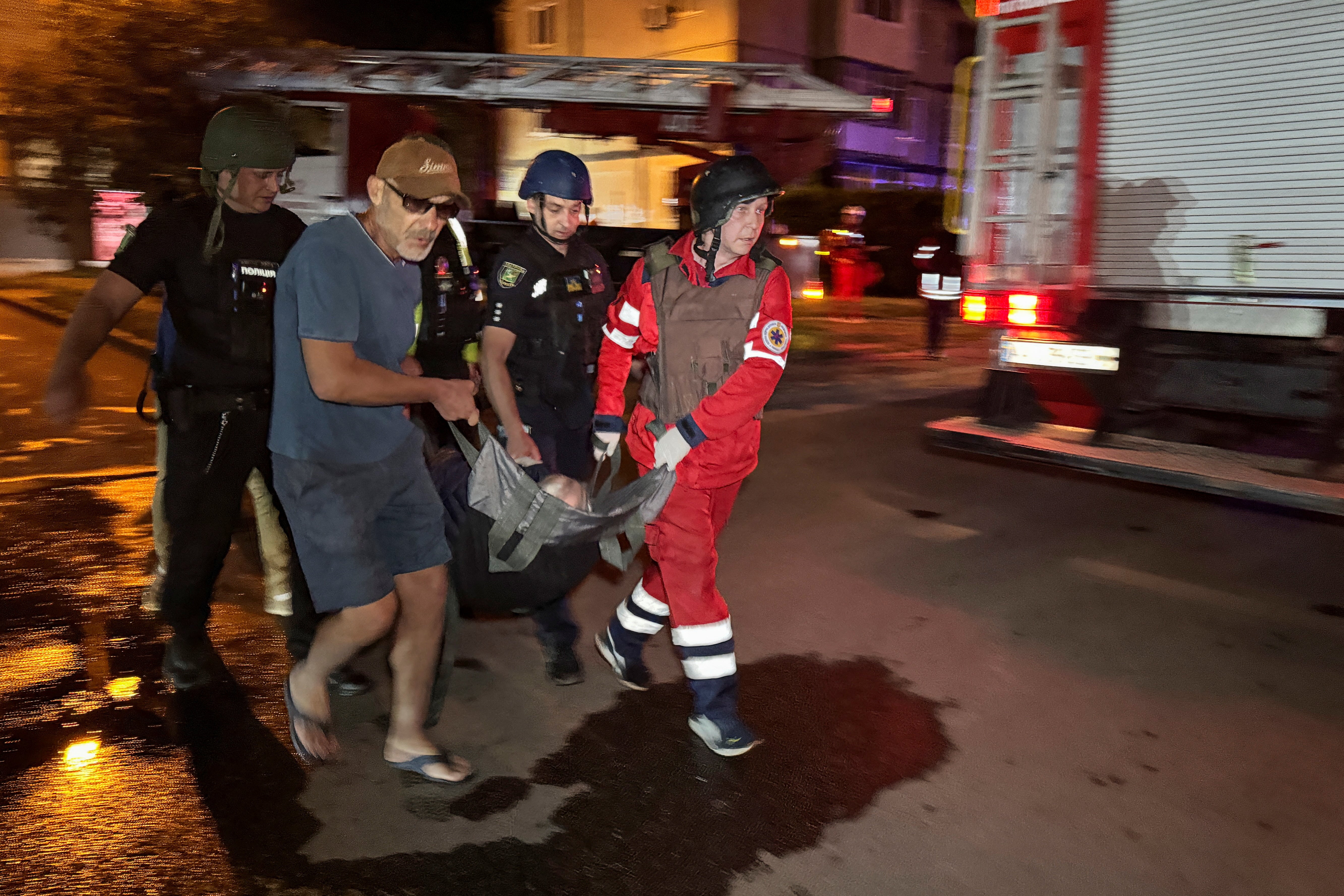 Emergency workers and volunteers carry a person evacuated from an apartment building damaged by a Russian drone strike, amid Russia's attack on Ukraine, in Kharkiv, Ukraine June 11, 2025