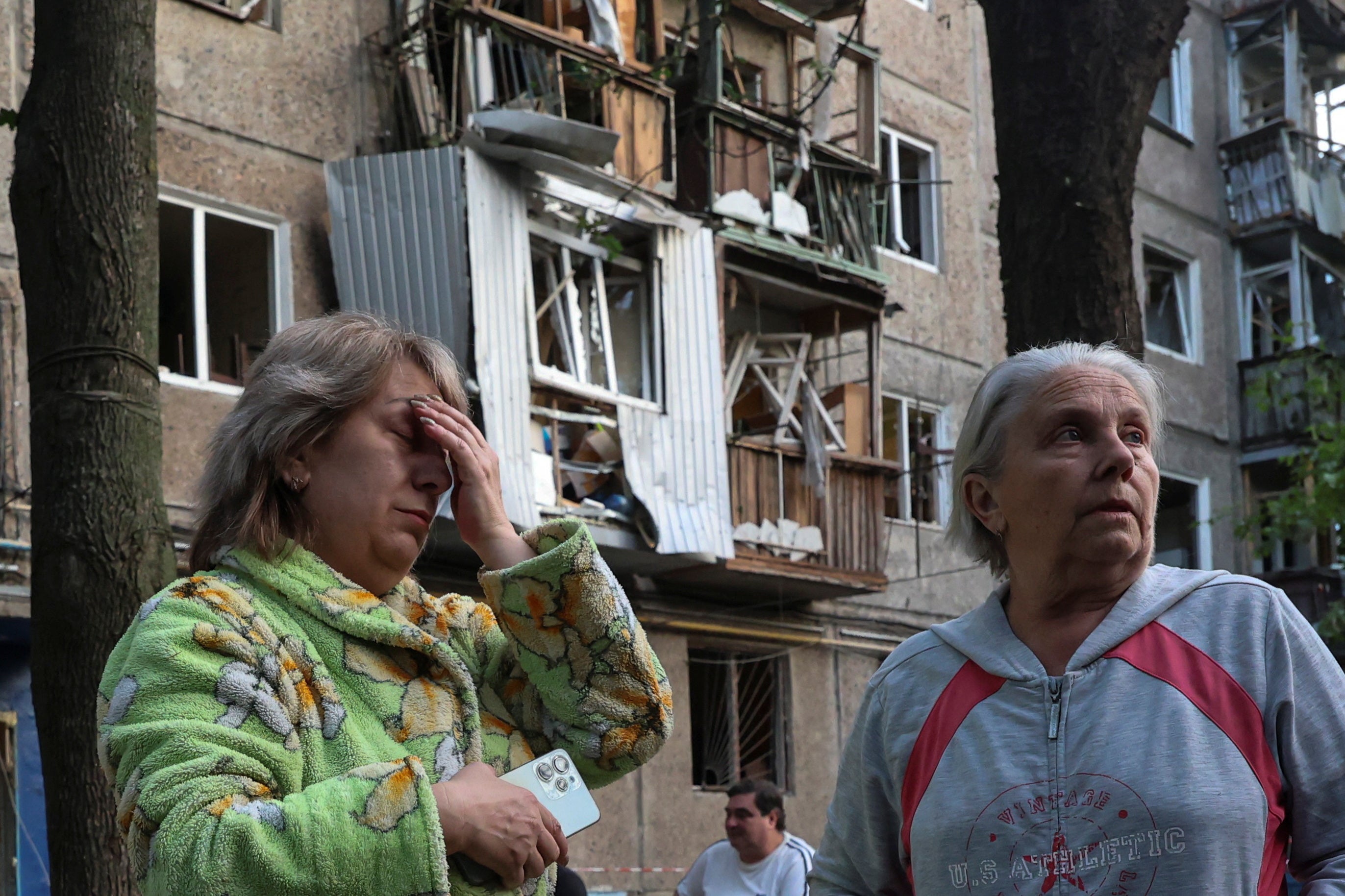 Women react next to their apartment building damaged by a Russian drone strike, amid Russia's attack on Ukraine, in Kharkiv, Ukraine June 11, 2025