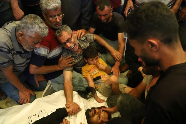 <p>Ata Qasas, center, mourns over the body of his son Rashad Qasas, who was killed near an aid distribution hub in Rafah, southern Gaza, on 11 June 2025</p>