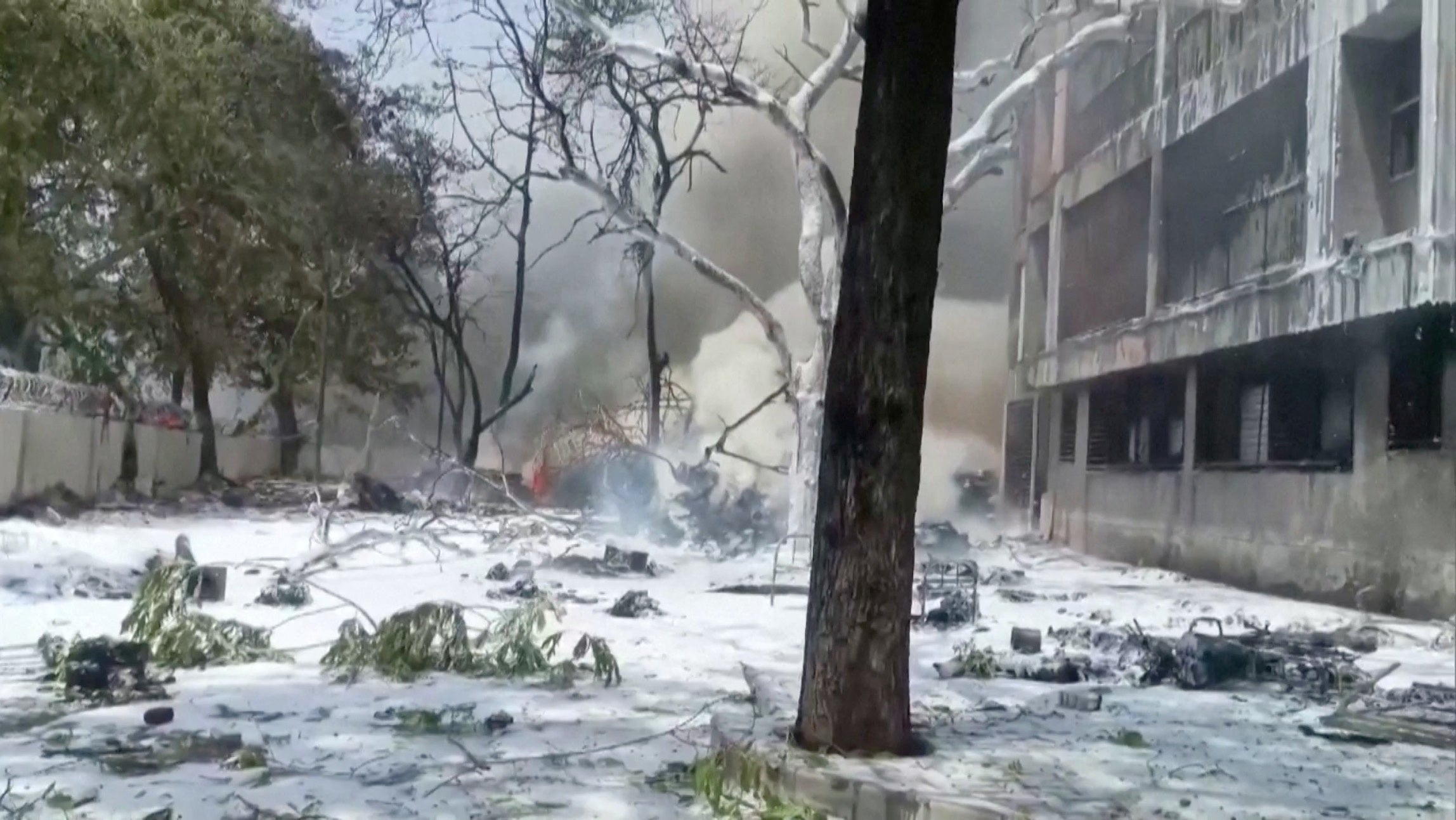Smoke rises near a damaged building and trees after an Air India plane crashed in Ahmedabad, India, on 12 June 2025