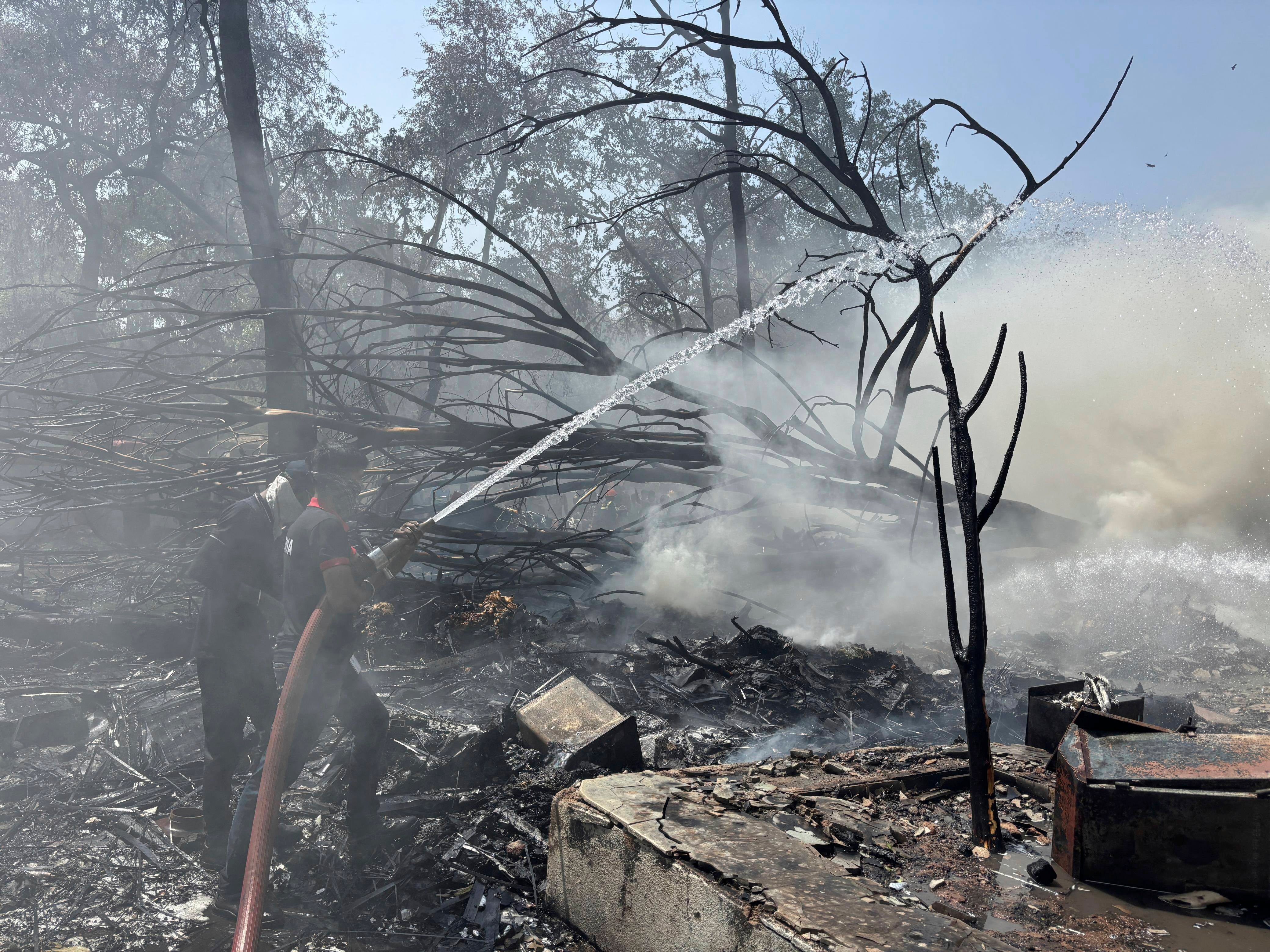 Firefighters work at the site of the crash scene near the airport