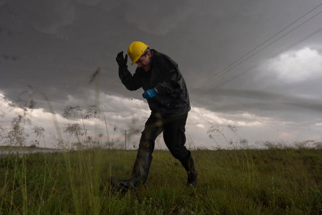 <p>Joey Toniolo ducks from falling hail as he moves back to Northern Illinois University's Husky Hail Hunter vehicle during a Project ICECHIP operation</p>