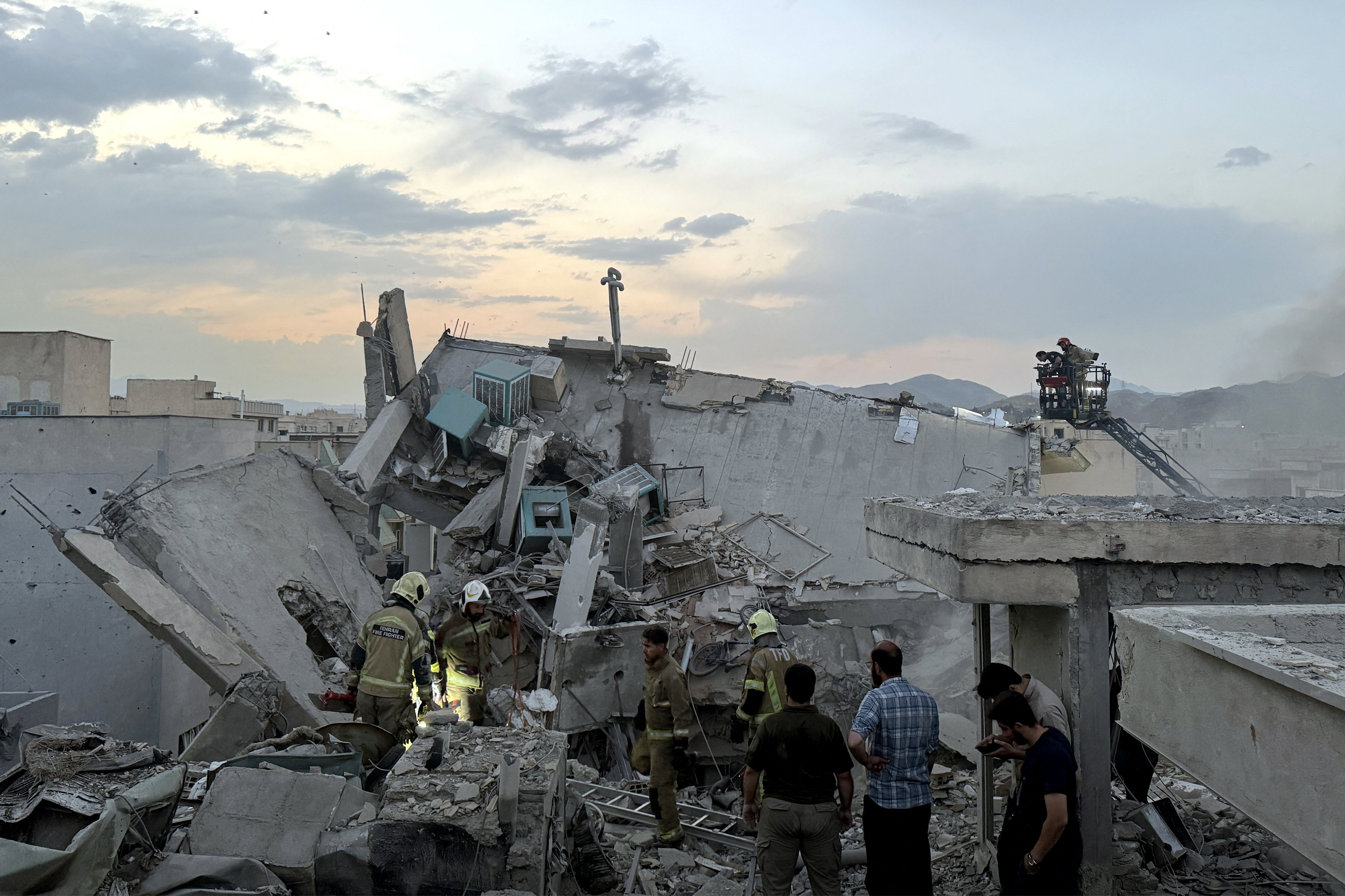 People and first-responders gather atop a building a that was hit by an Israeli strike in Tehran on June 13, 2025