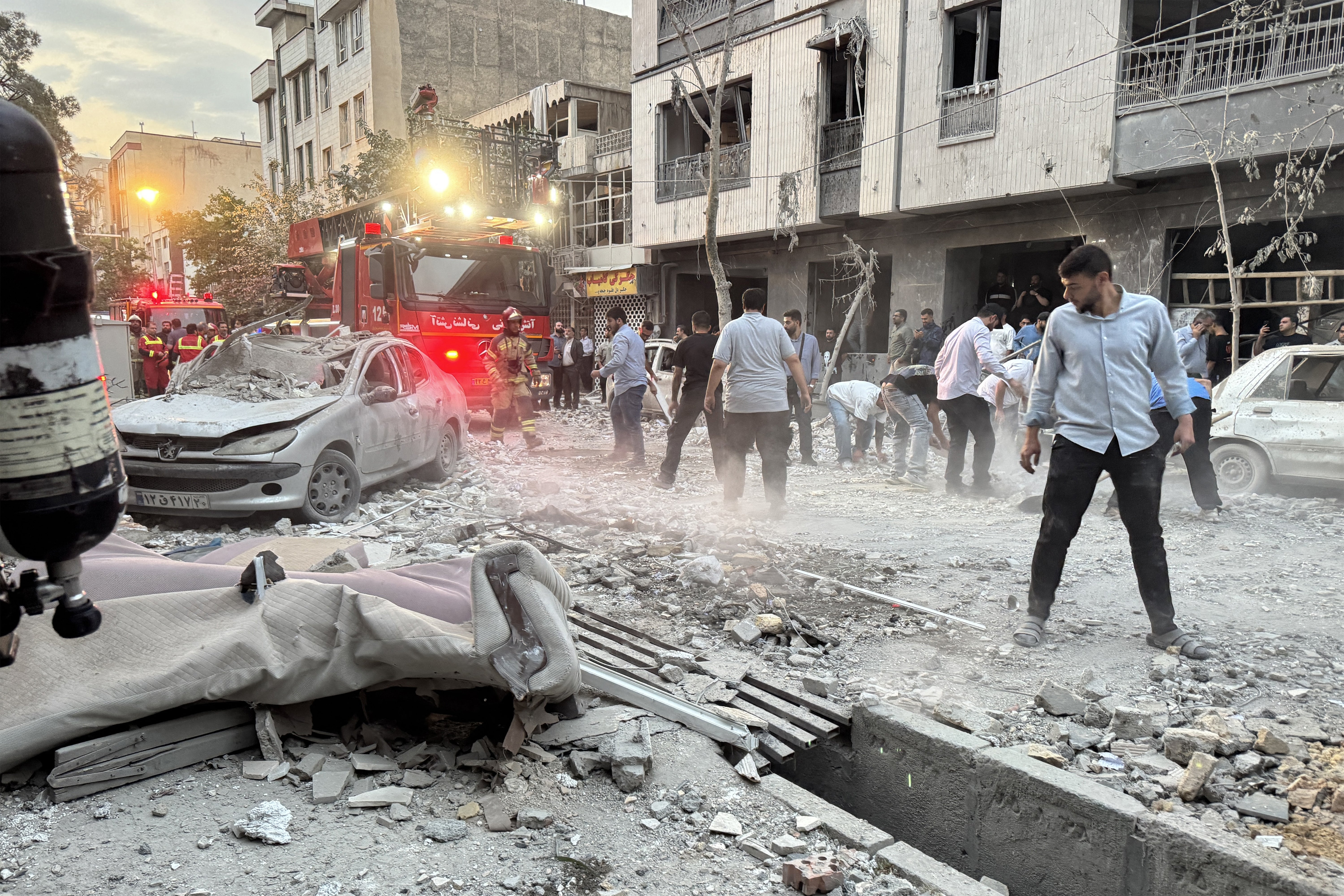 People and first-responders gather outside a that was hit by an Israeli strike in Tehran on June 13, 2025