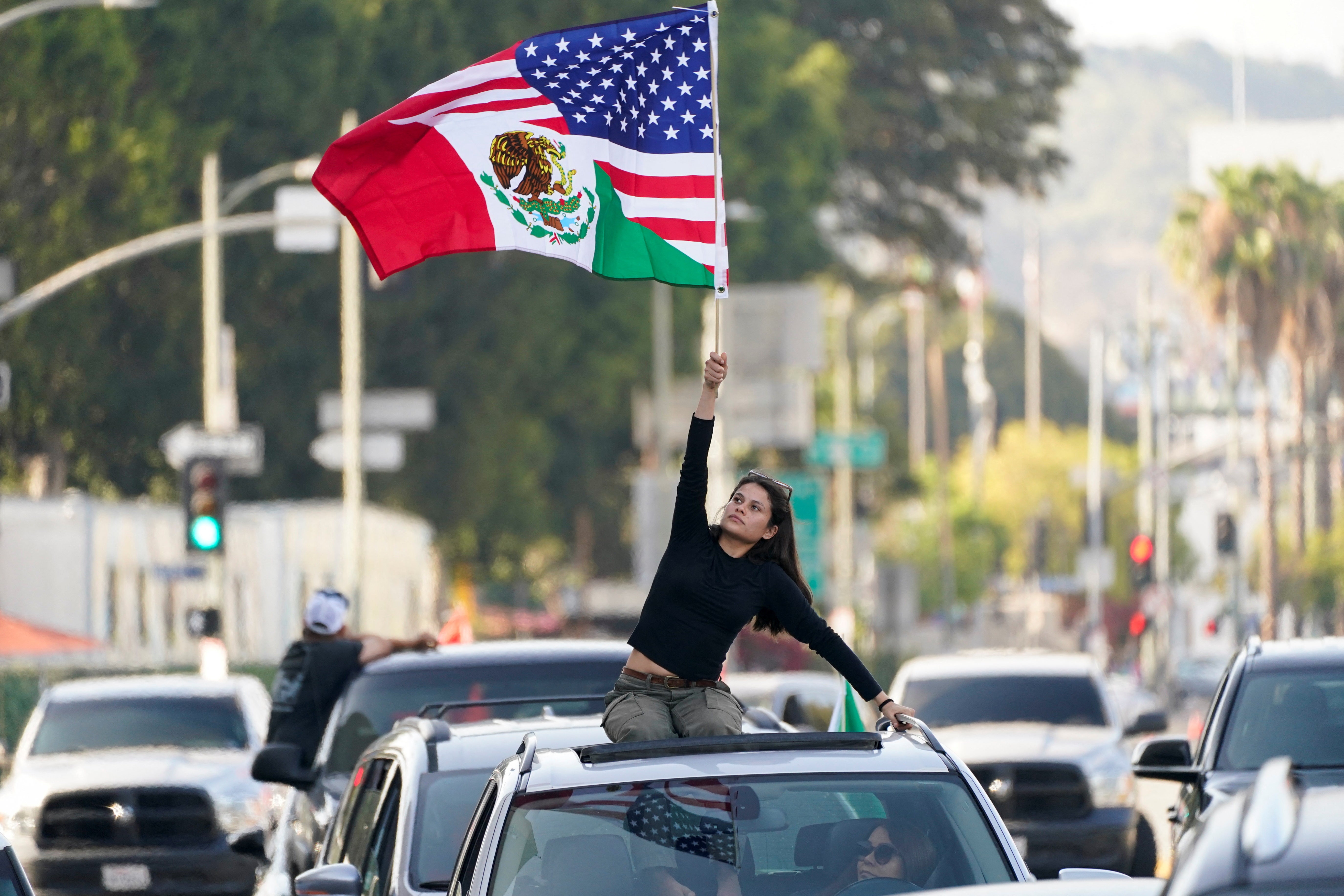 A person waves a mixed U.S.-Mexico flag during a protest against federal immigration sweeps in LA
