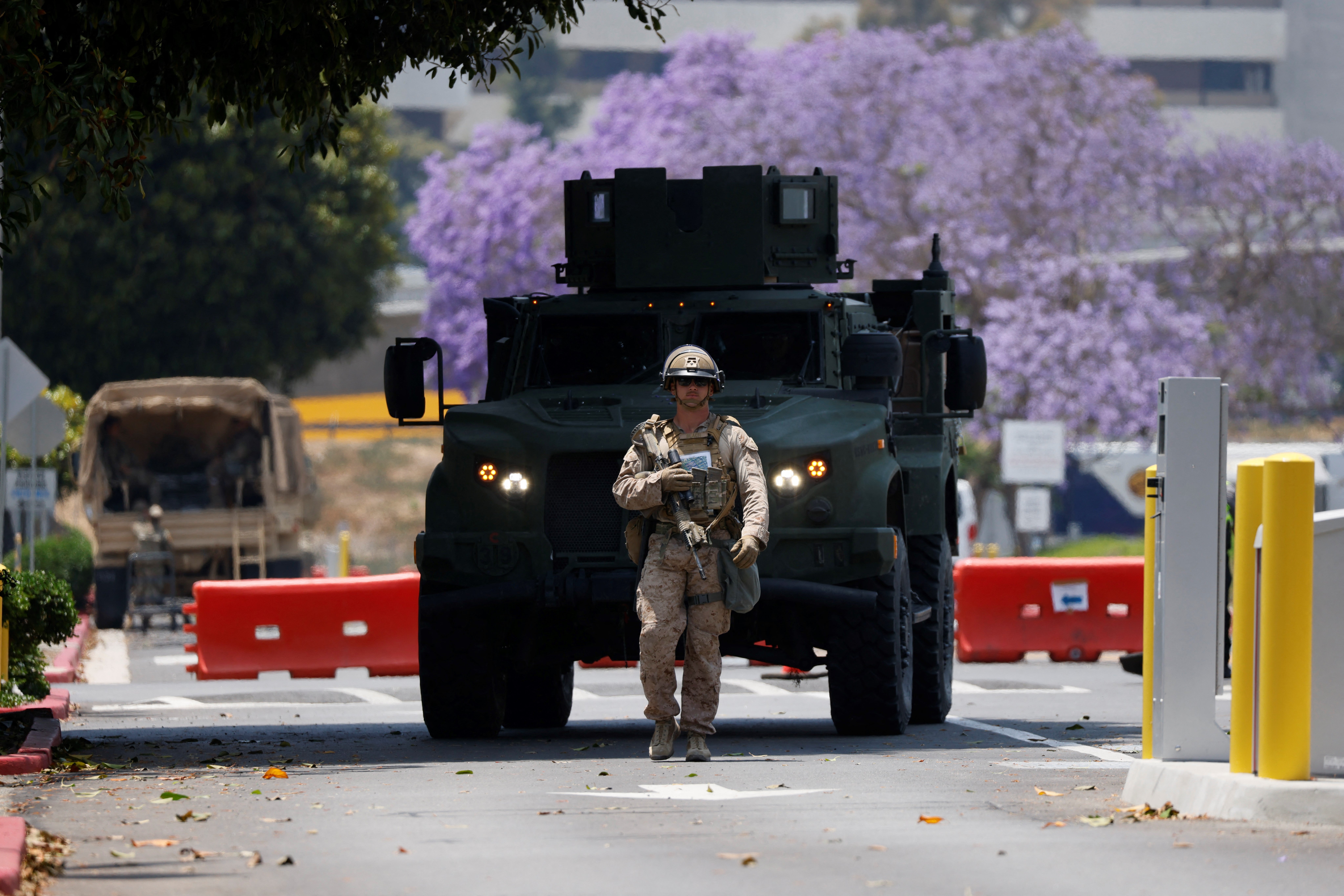 A US Marine walks in front of an armored vehicle on the parking lot of the Wilshire Federal Building in Los Angeles