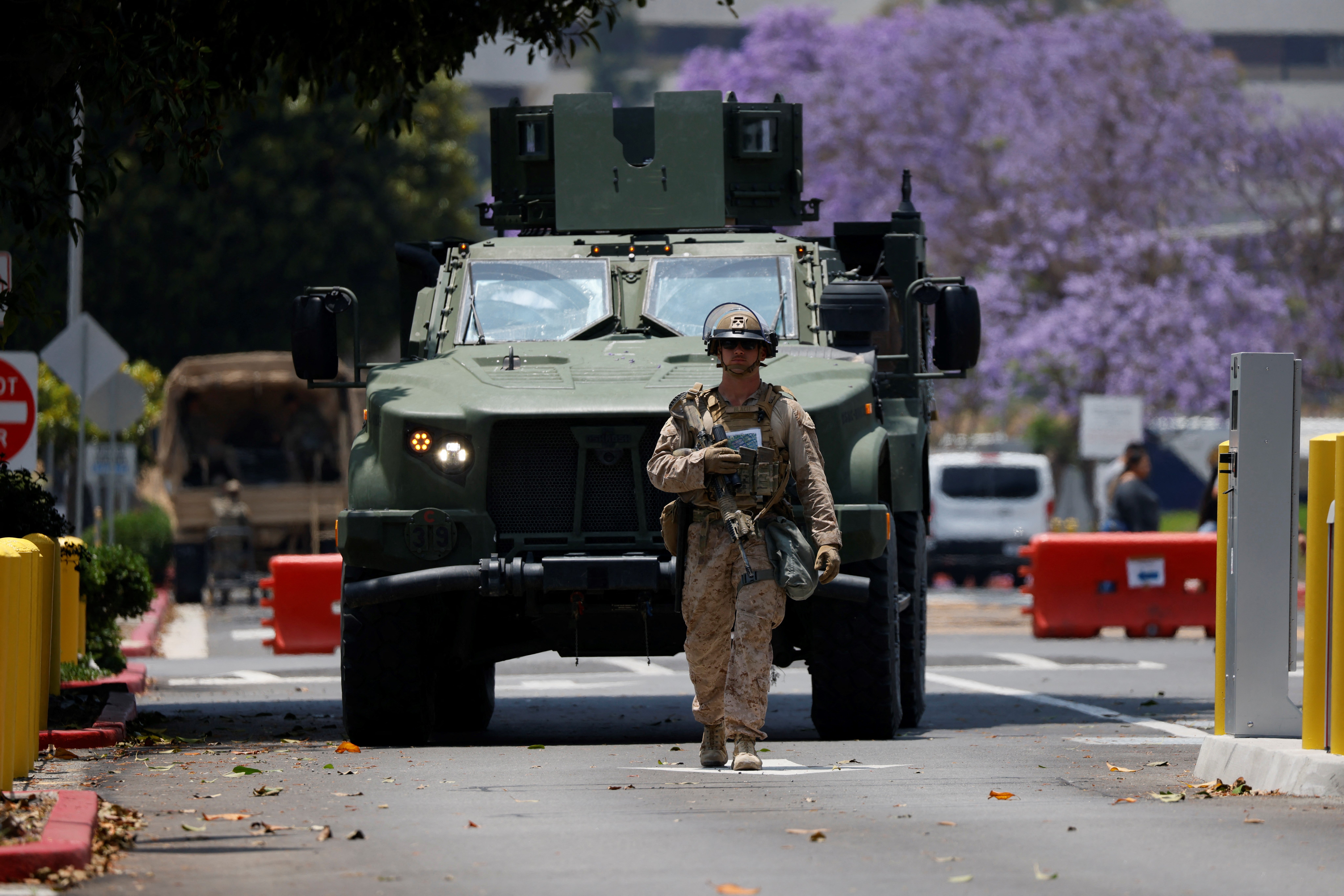 A US Marine walks in front of an armored vehicle on the parking lot of the Wilshire Federal Building in Los Angeles on Friday