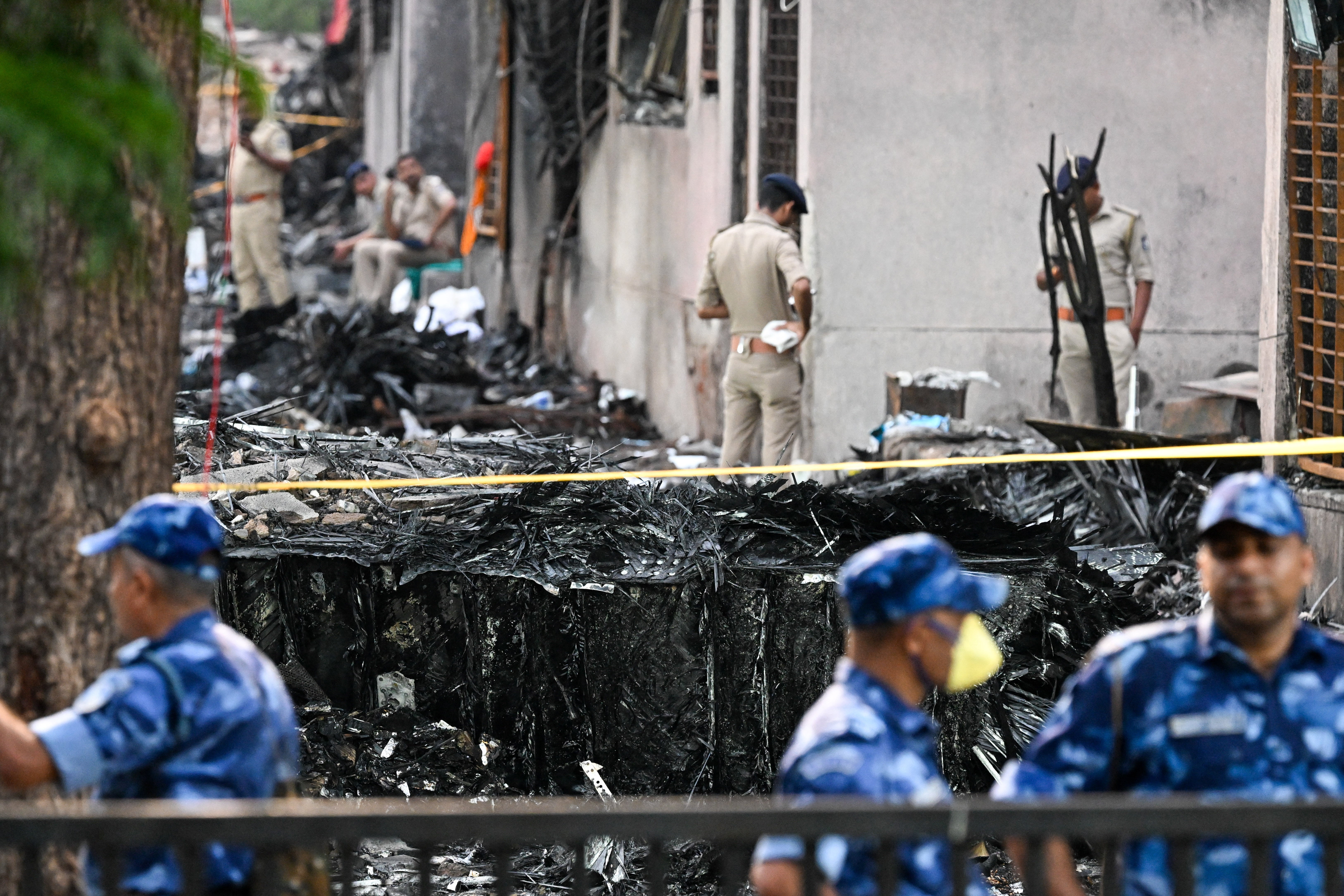 Police stand guard crashed in a residential area near the airport in Ahmedabad near the wreck on the site after Air India Flight 171
