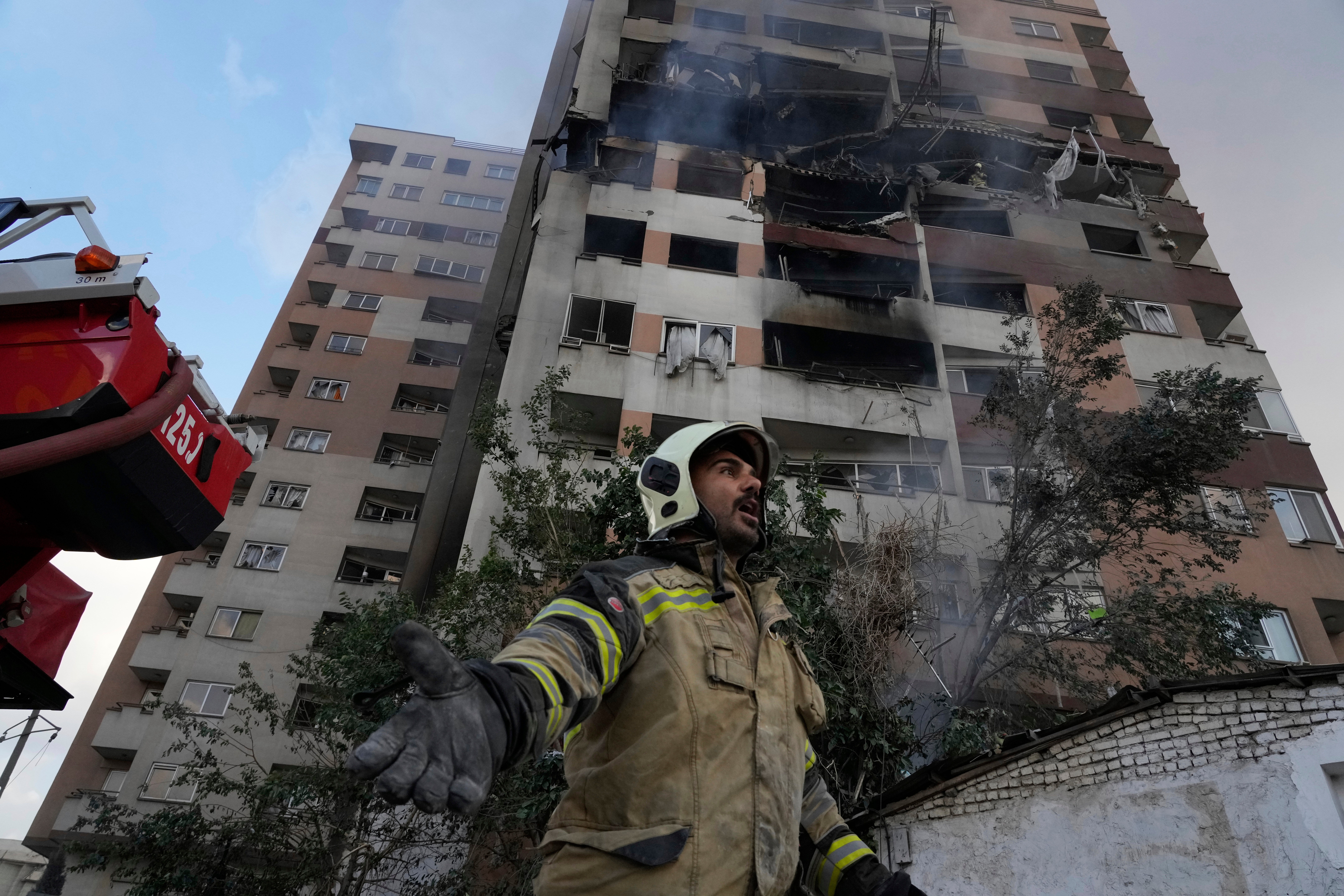 A firefighter calls out his colleagues at the scene of an explosion in a residence compound in northern Tehran, Iran