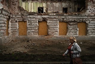 A woman walks past a monument destroyed by Russian bombing in Sumy in north-eastern Ukraine