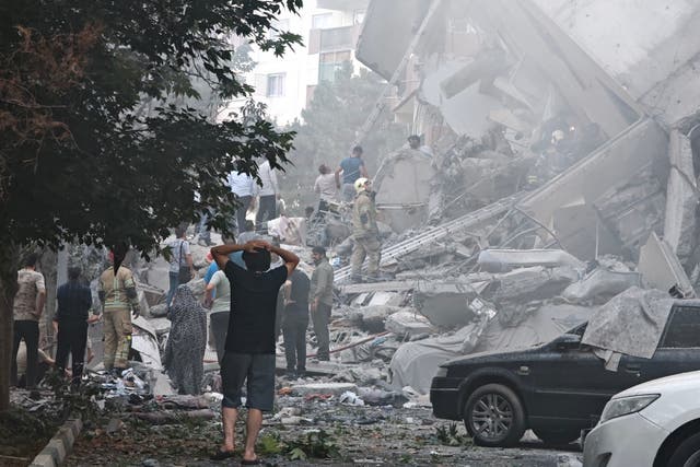 <p>People look over damage to buildings in Nobonyad Square following Israeli airstrikes on Tehran</p>